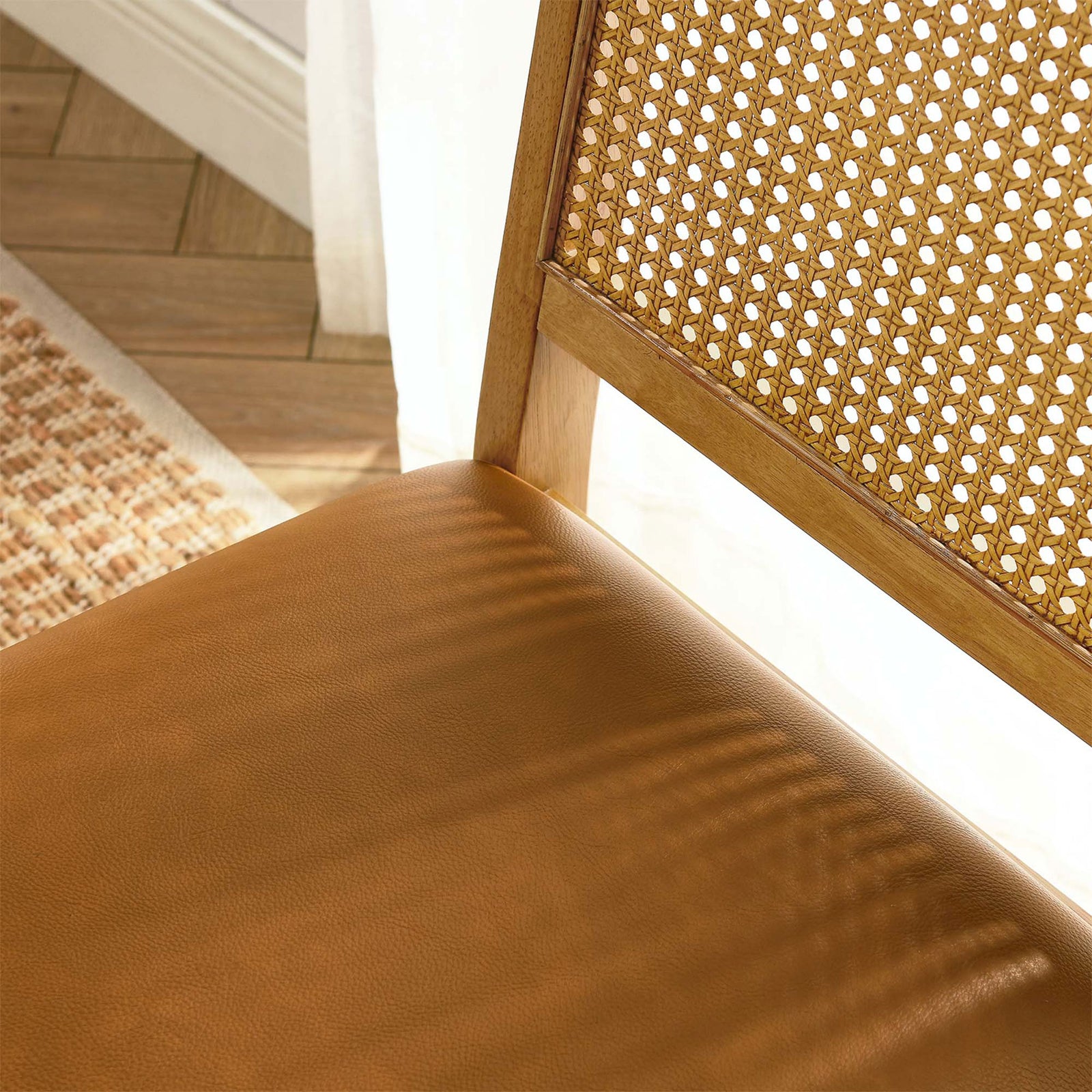 Sunlit dining scene focusing on the tan vegan leather seat and natural cane back texture || EEI-6802-NAT-NAT-TAN || detail_room