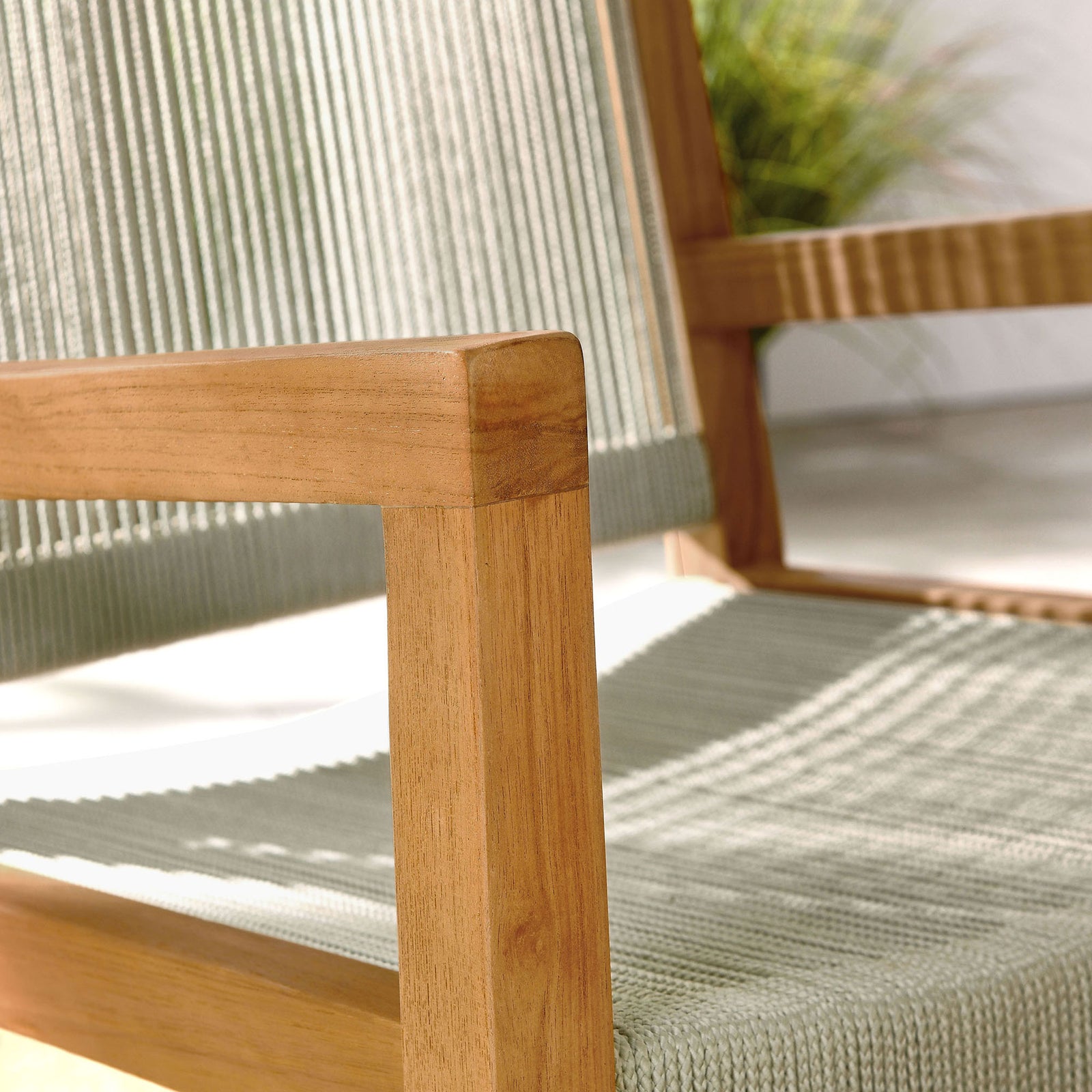 Sunlight accentuates the texture of the natural rope seat and teak arm on a serene patio setting || EEI-6806-NAT-NAT || detail_room