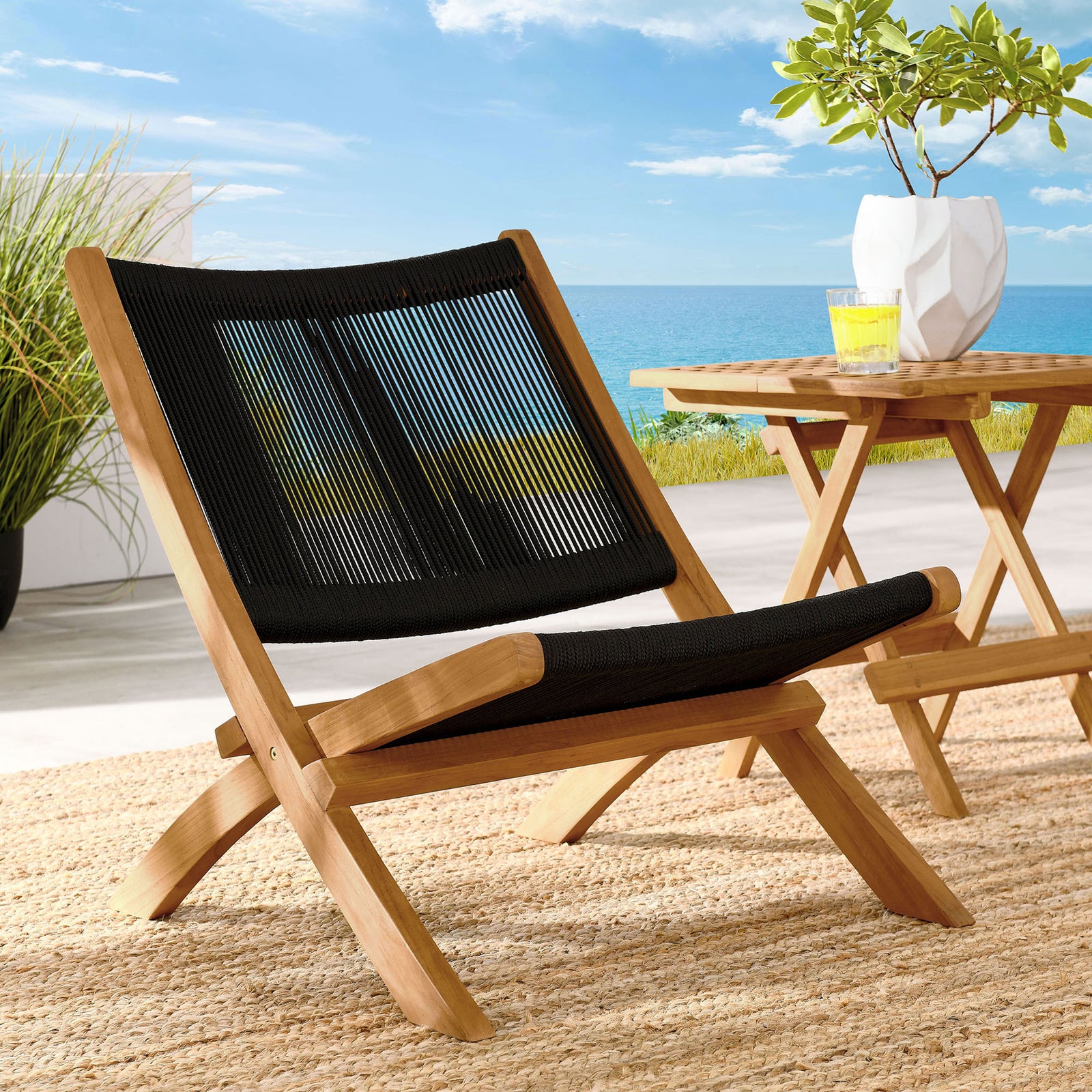 Teak and black rope lounge chair adds modern comfort to a bright coastal patio setting || EEI-6808-NAT-BLK || front_angle_room