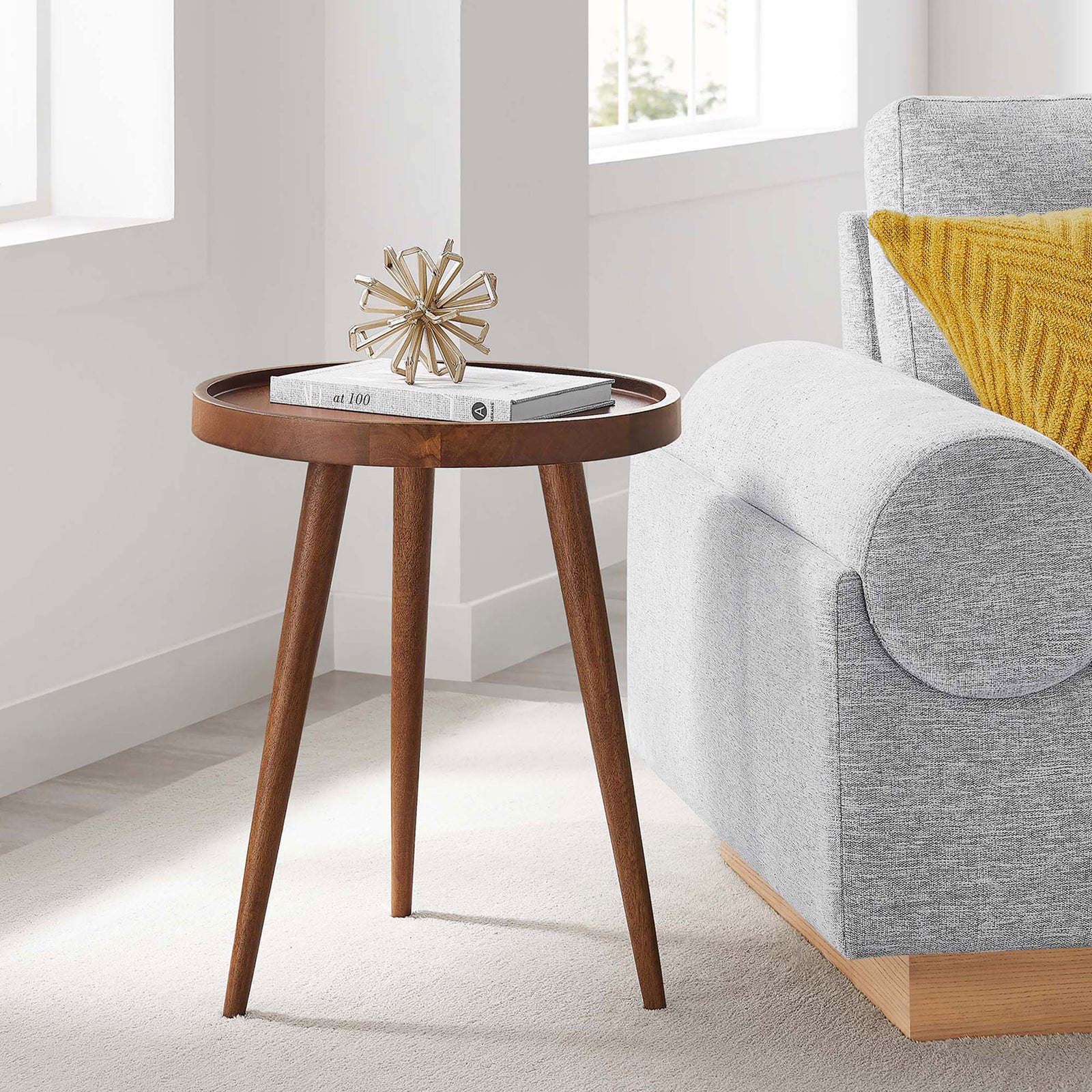 Round walnut side table with tripod legs and raised tray top brings mid-century charm beside a cozy sofa || EEI-6830-WAL || front_angle_room