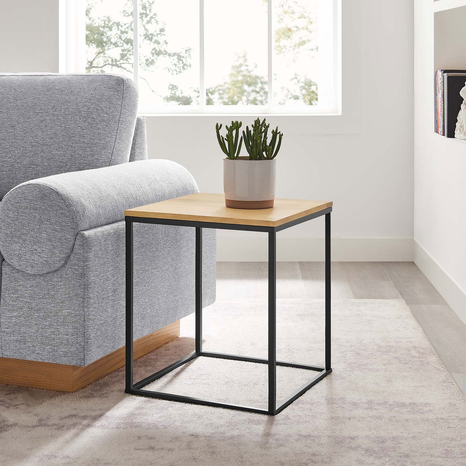 Oak wood and black metal side table styled next to a sofa for modern living room decor || EEI-6833-OAK || front_angle_room