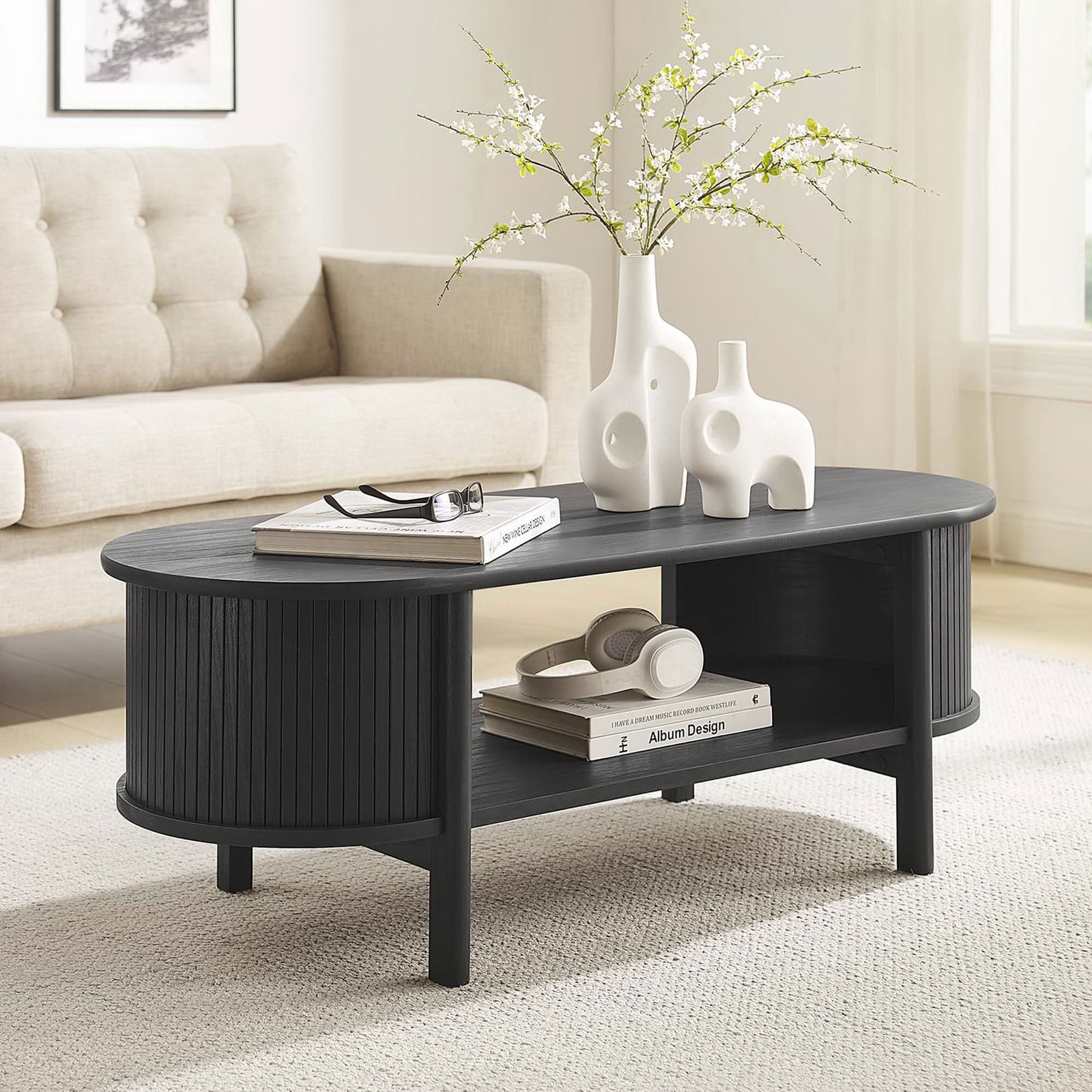 Grounds the living room with its deep black finish, roomy shelf, and inviting oval form. || EEI-6837-BLK || front_angle_room