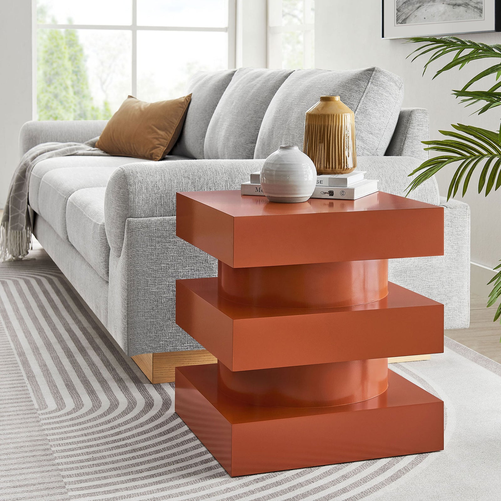 Cayenne Perpetuate end table anchoring a modern living room beside a plush gray sofa and patterned area rug. || EEI-6864-CAY || front_angle_room