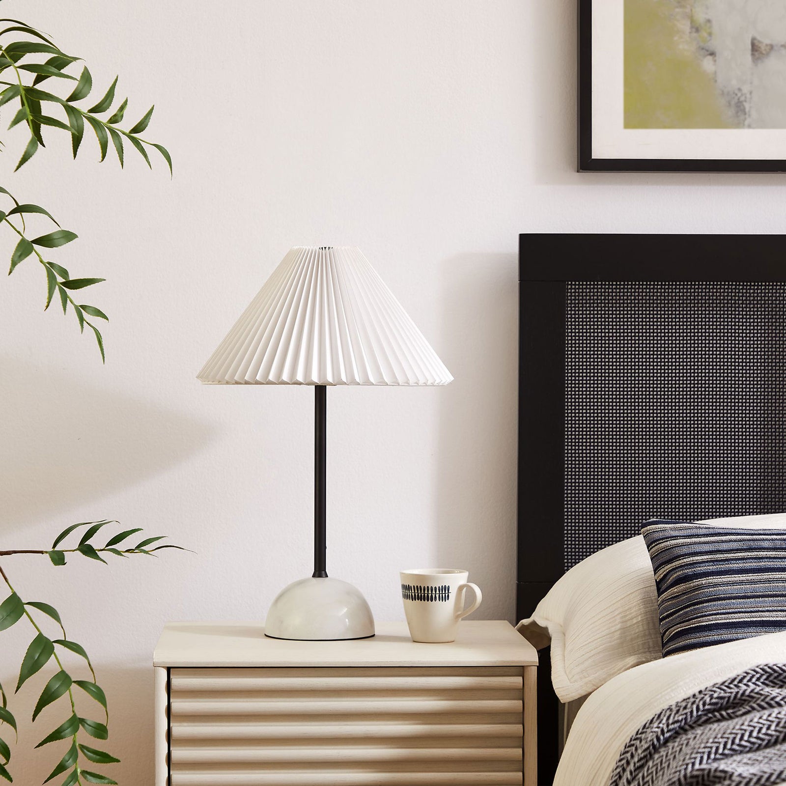 Illusion lamp styling a bedside table with its sculpted marble base and crisp pleated shade. || EEI-6878-BLK || front_angle_room