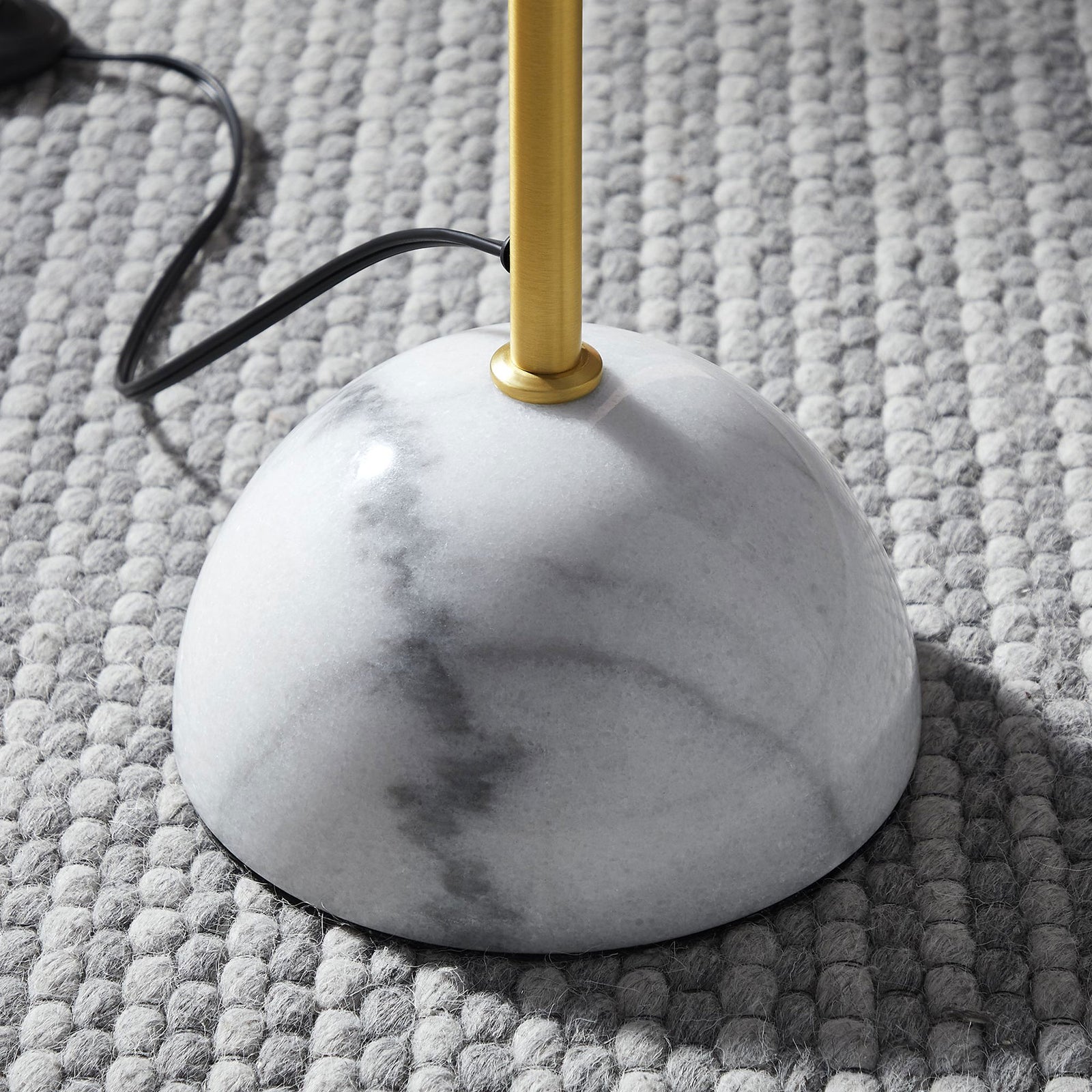 Marble dome base and brass stem of floor lamp resting on a textured gray rug || EEI-6879-BRA || detail_room