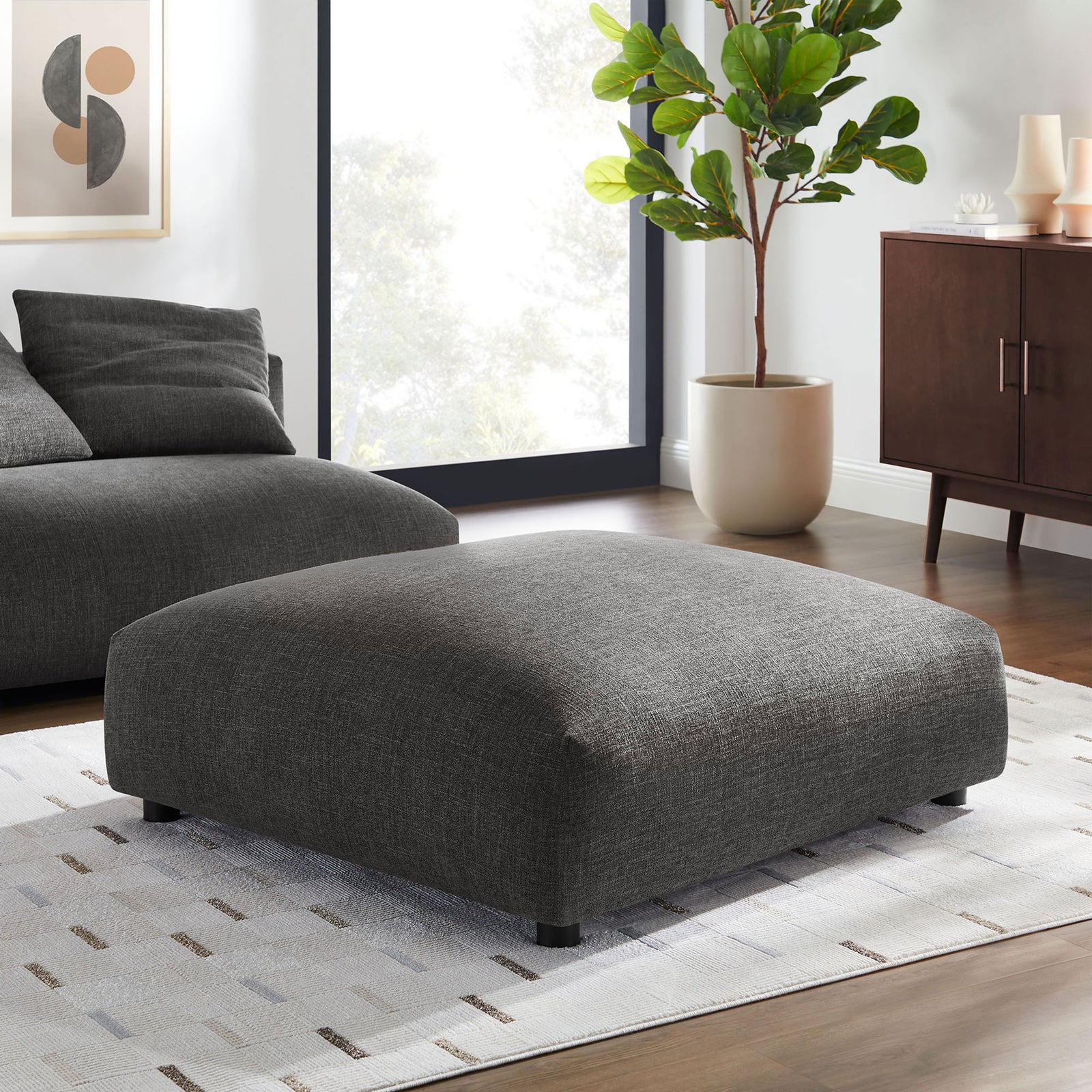 Charcoal modular ottoman anchored on a light rug beside a low-profile sofa in a modern living room || EEI-6889-CHA || front_angle_room
