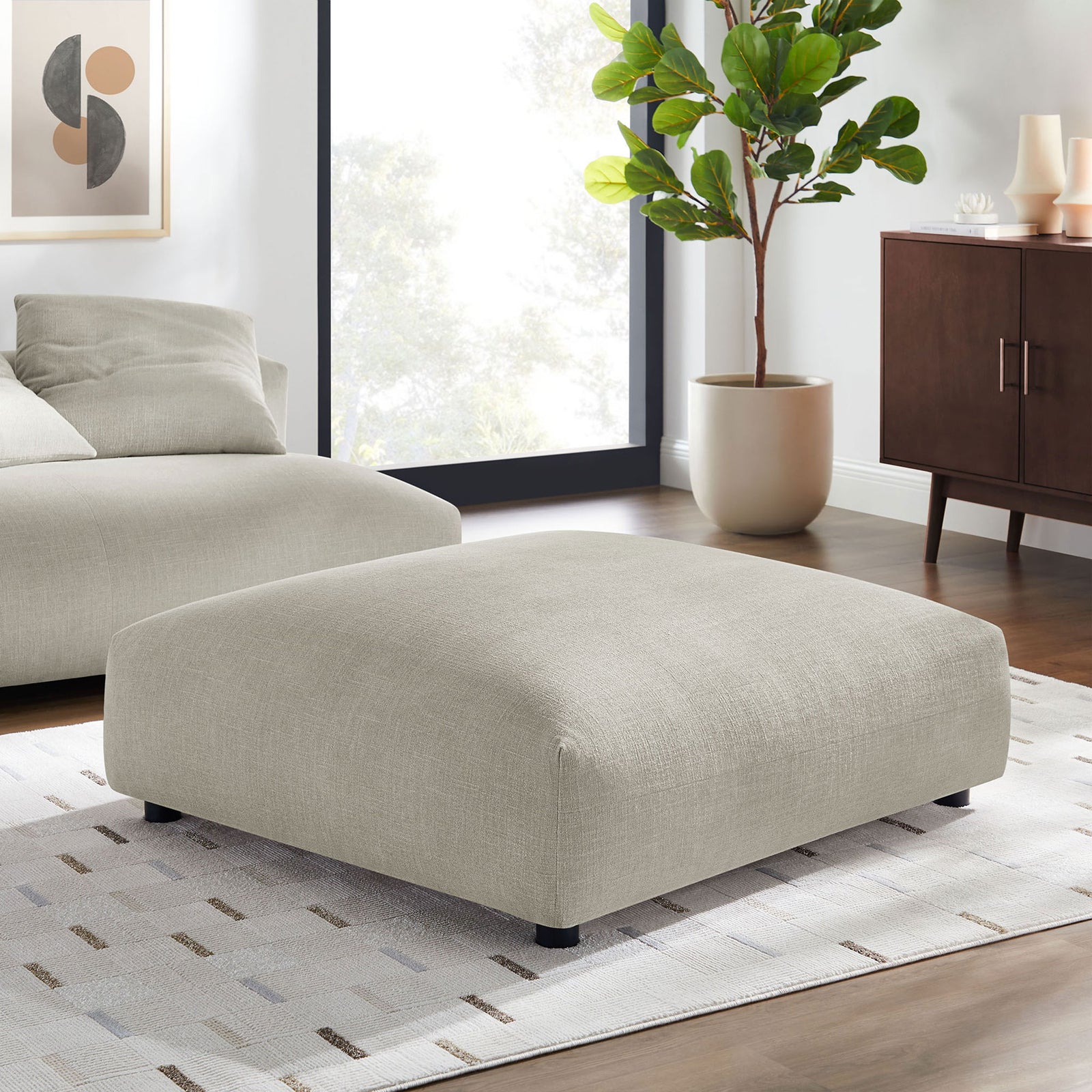 Linen modular ottoman anchors a bright living room, adding relaxed modern style and versatile lounging or table space || EEI-6889-LIN || front_angle_room