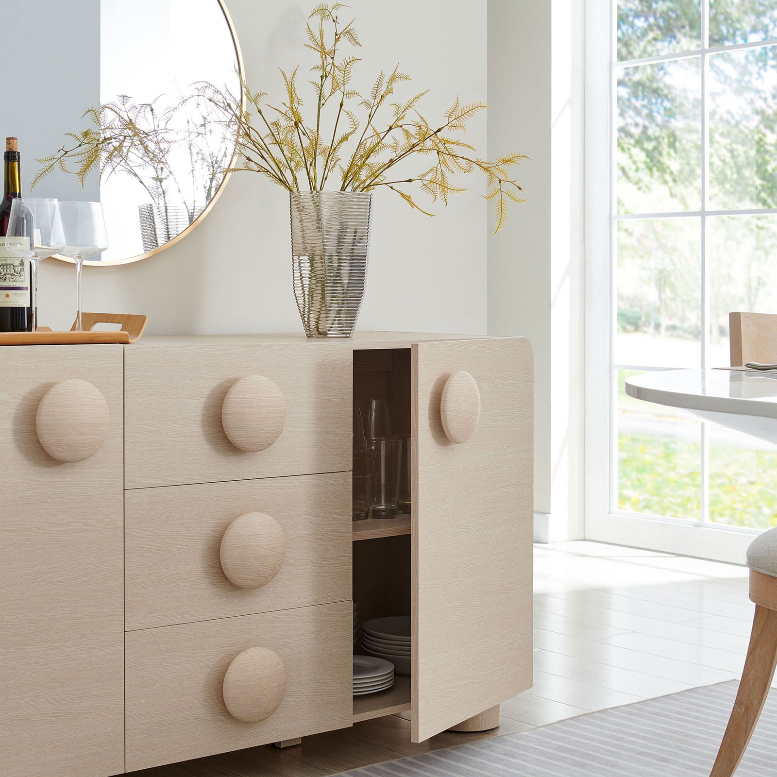 Sonnet ash sideboard styled in a bright dining room with cabinet storage open for serveware and glassware. || EEI-6892-ASH || front_angle_open_room
