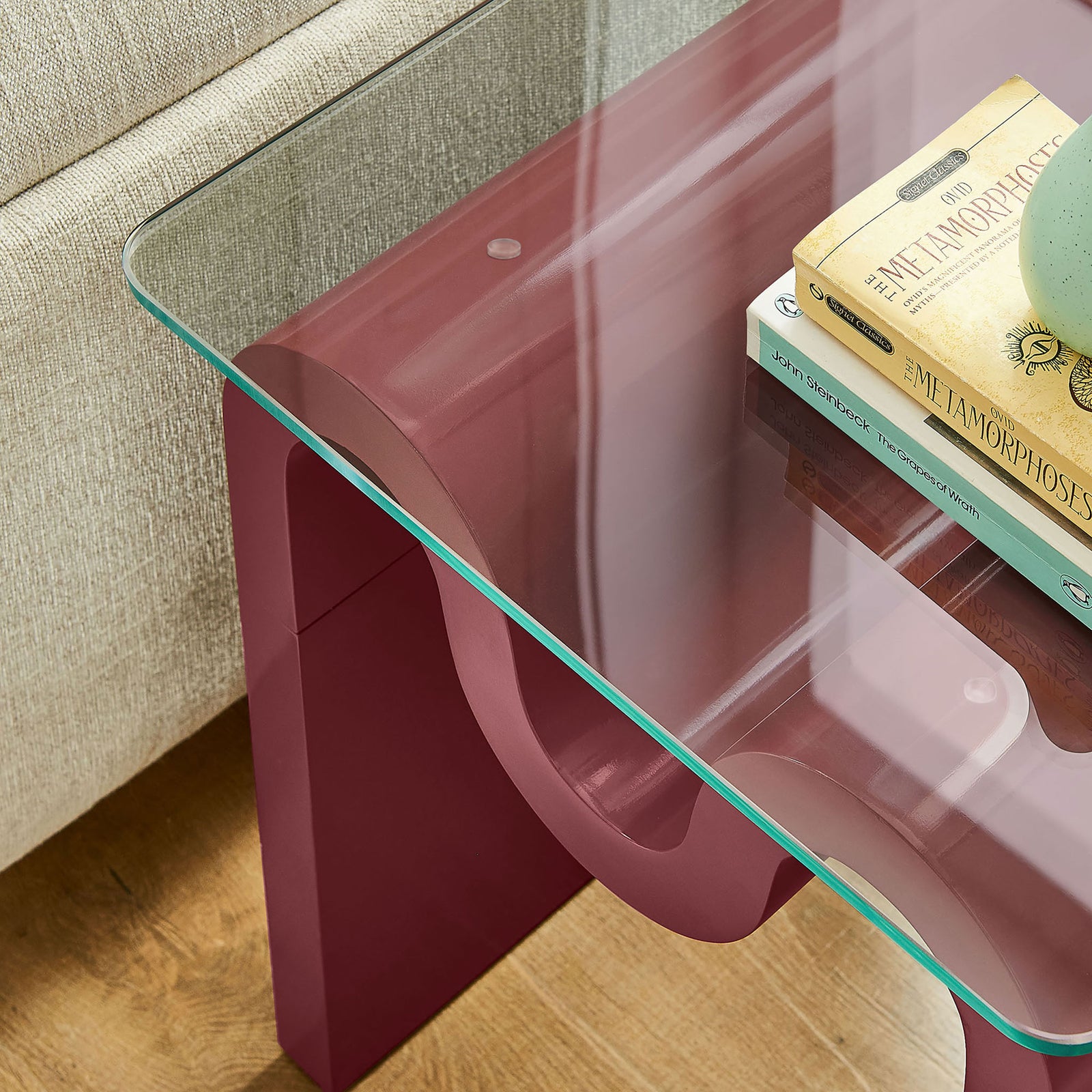 Ondine side table styled with books and decor, highlighting the clear glass top and sculptural base || EEI-6902-SPA || detail_room