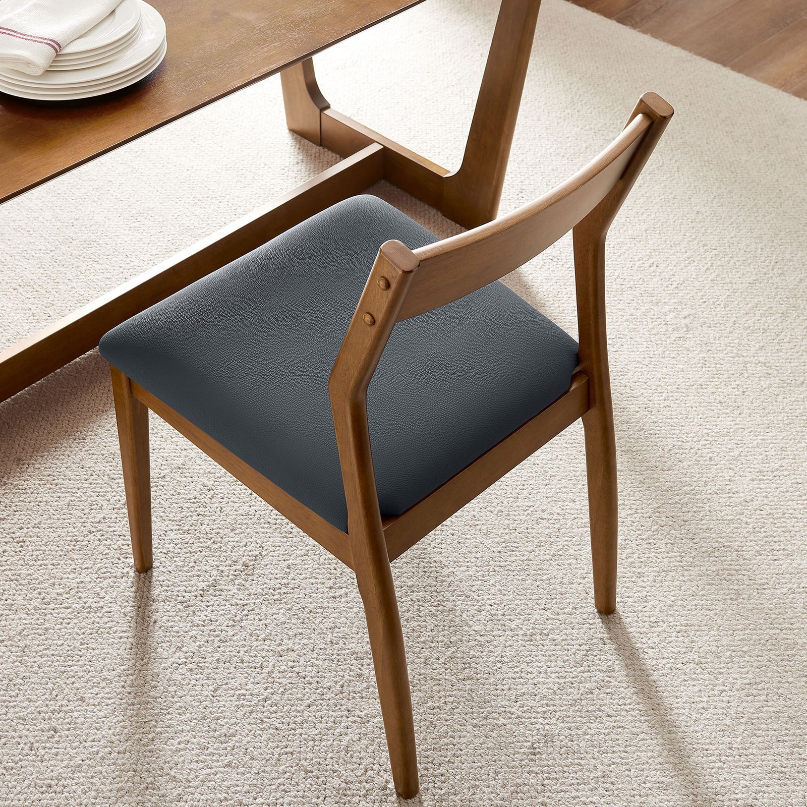 Walnut dining chair with black vegan leather seat styled at a warm wood dining table. || EEI-6917-WAL-BLK || top_angle_room