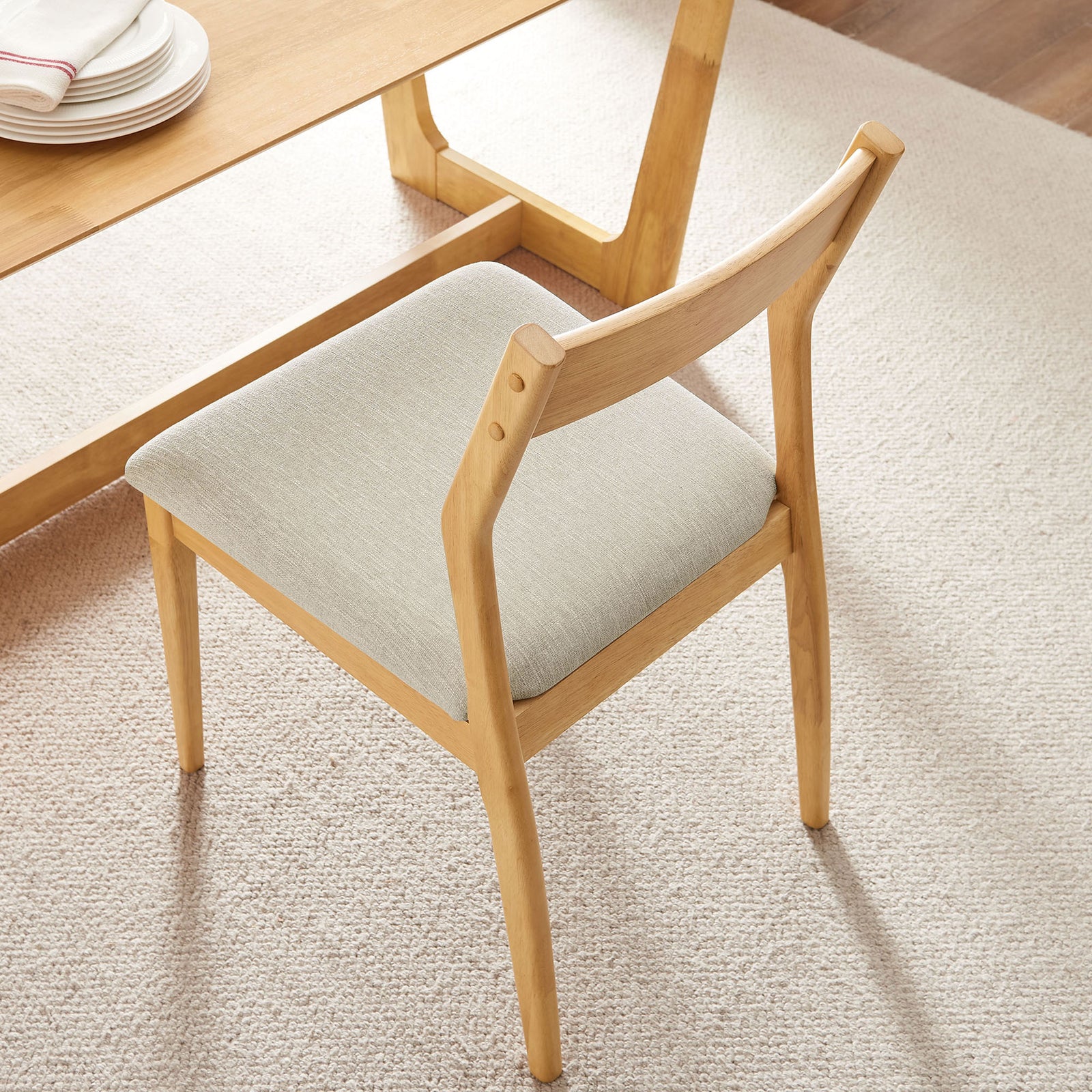 Natural wood dining chair with beige upholstered seat styled beside a matching table on a light rug || EEI-6918-NAT-HEB || top_angle_room