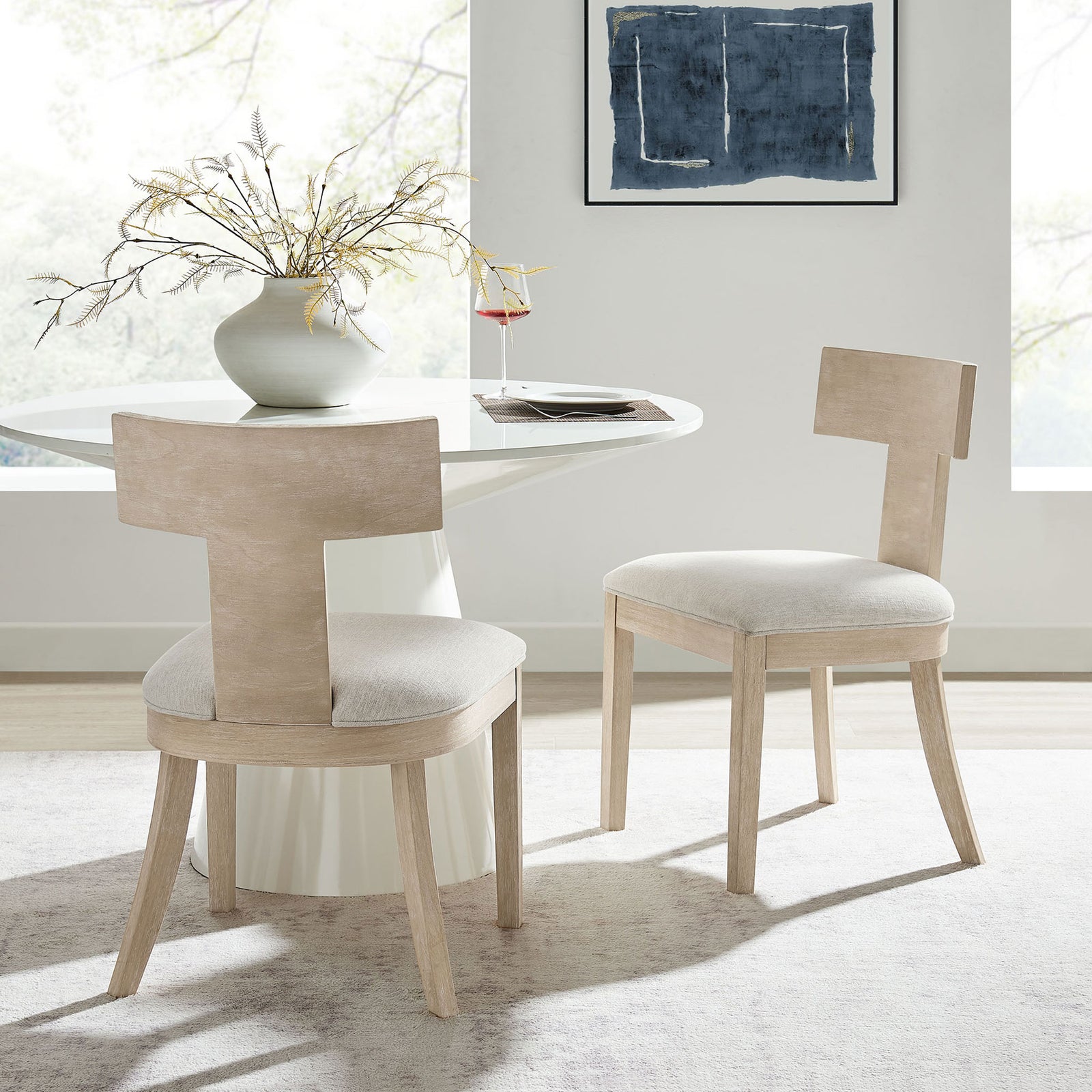 Peregrine dining chairs paired with a round table in a bright dining room over a soft area rug || EEI-6923-NAT-HEI || front_angle_multi_room