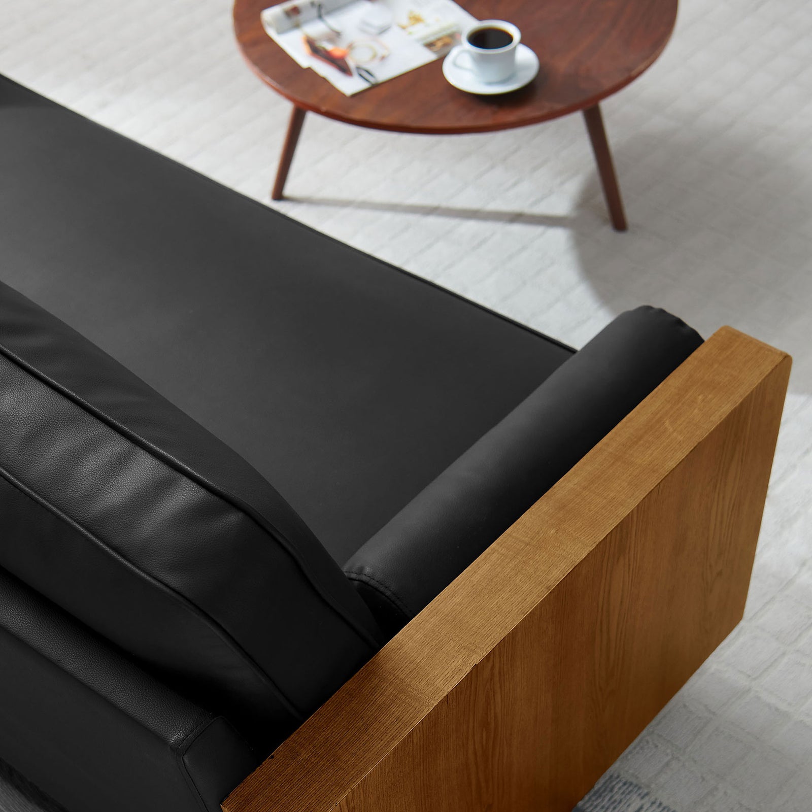 Sofa corner showing black vegan leather, walnut arm, and cozy modern living room setting || EEI-6942-WAL-BLK || detail_room