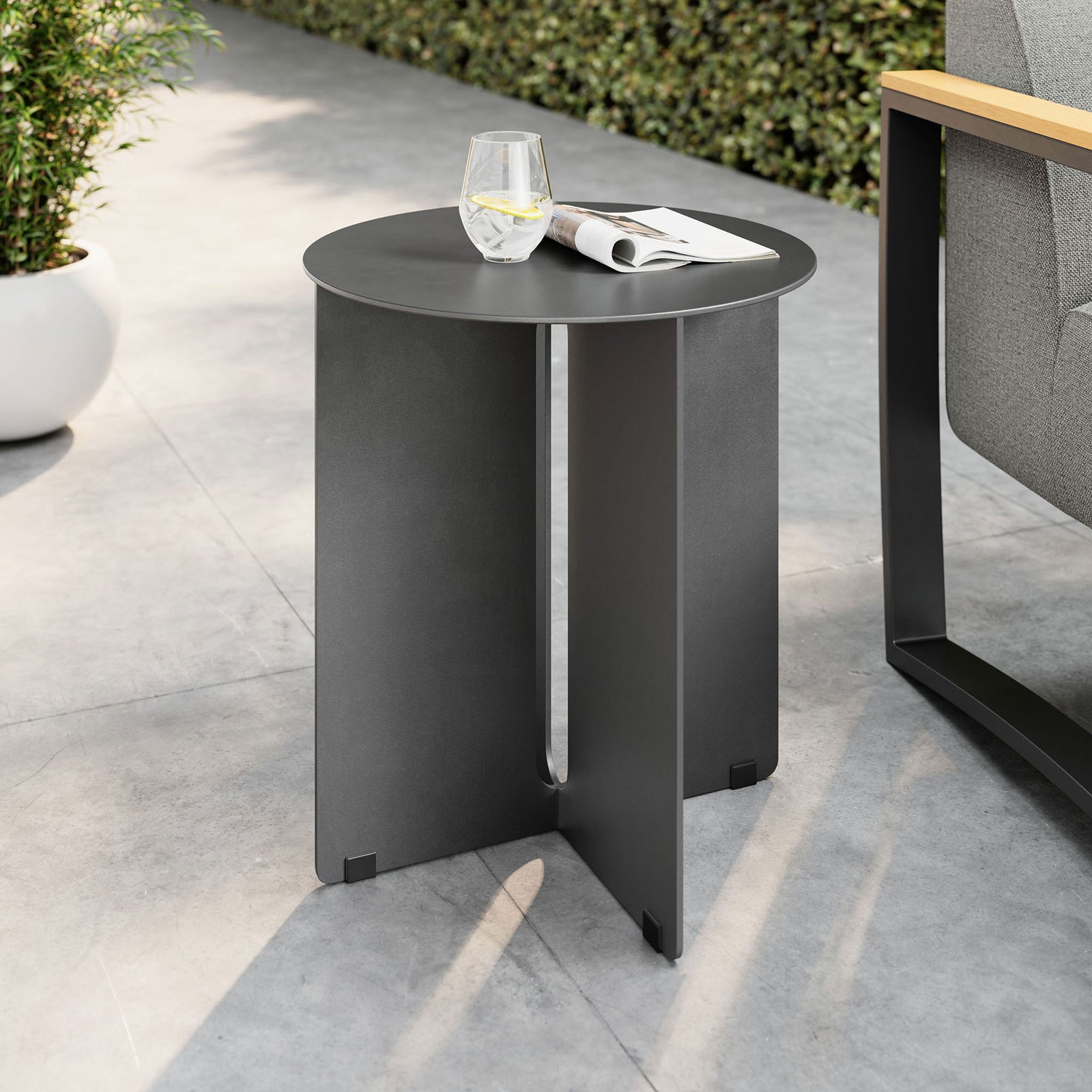 Charcoal metal outdoor side table beside cushioned lounge chair on modern patio || EEI-6946-CHA || front_angle_room