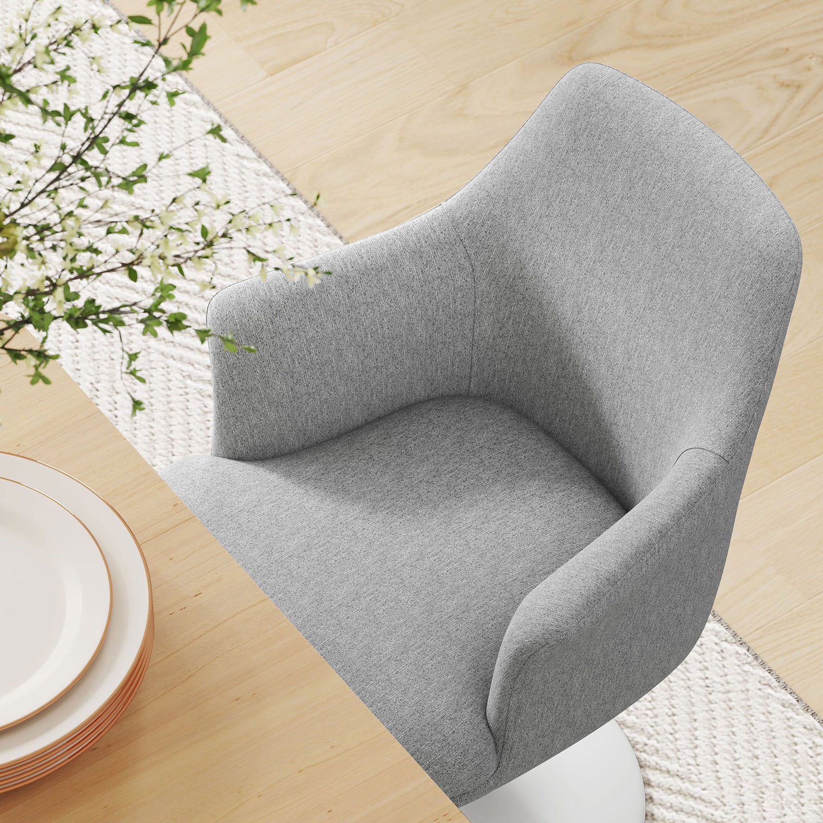 Padded gray seat and wraparound back of the swivel armchair styled at a bright dining table setting. || EEI-6956-WHI-HLG || detail_room
