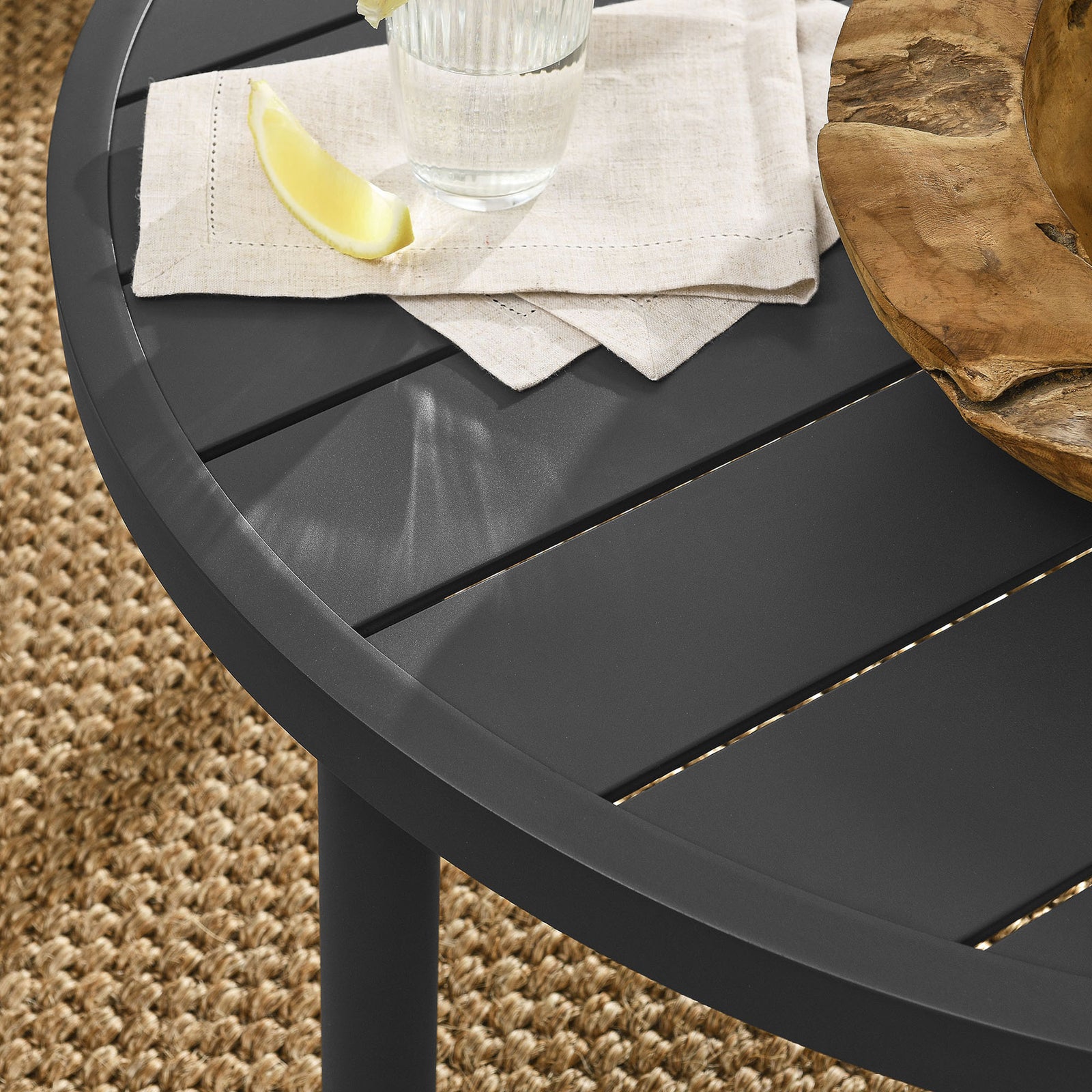 Graphite slatted coffee table styled with drink and decor on woven outdoor rug || EEI-6978-GPH || detail_room