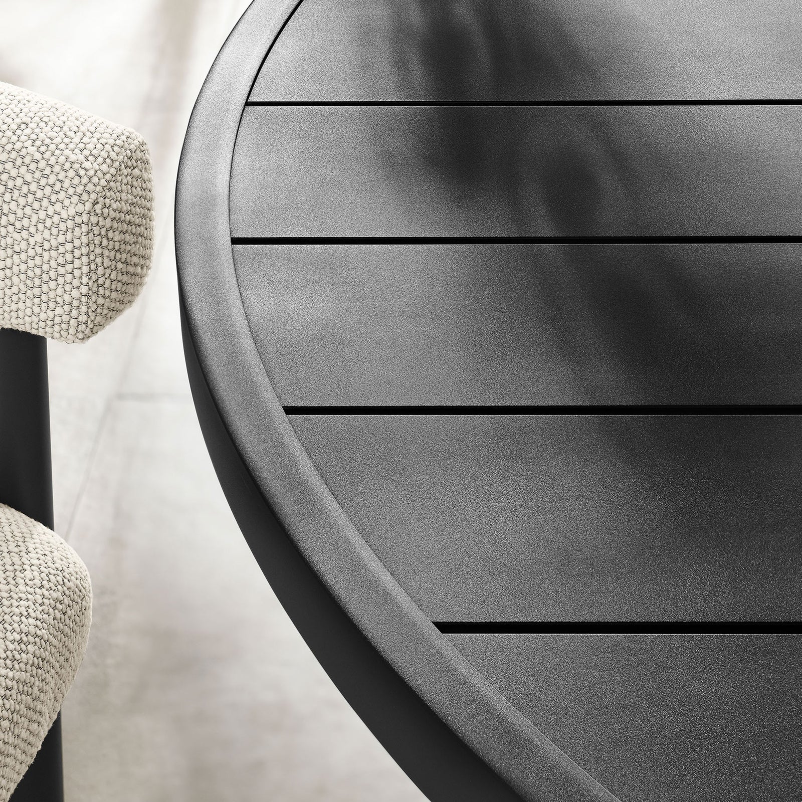 Graphite slatted round tabletop with soft matte texture, styled with greenery above light stone tile flooring || EEI-6981-GPH || detail_room