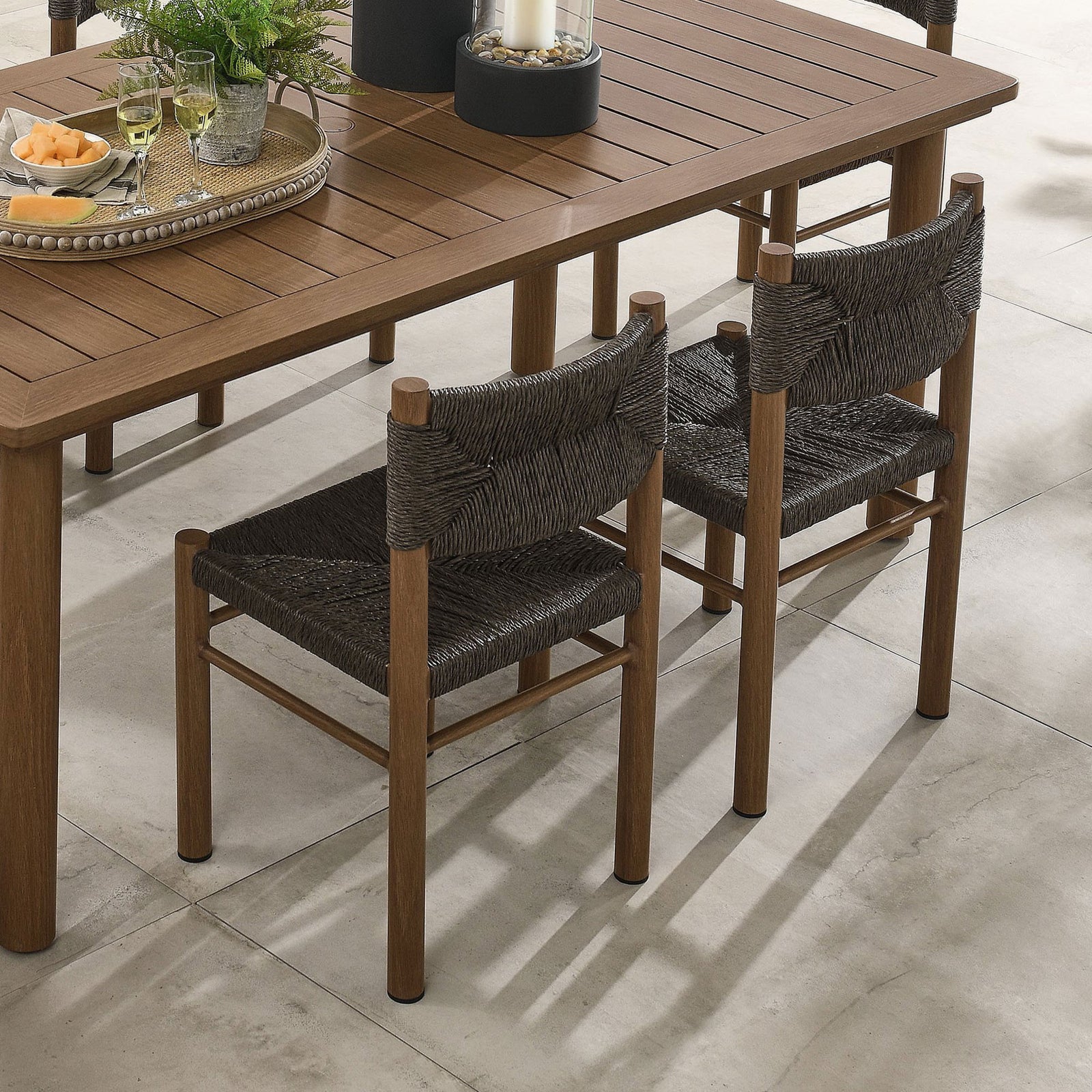 Set of two walnut rattan dining chairs paired with a wood grain table for a unified outdoor dining space || EEI-6982-WAL || front_angle_multi_room