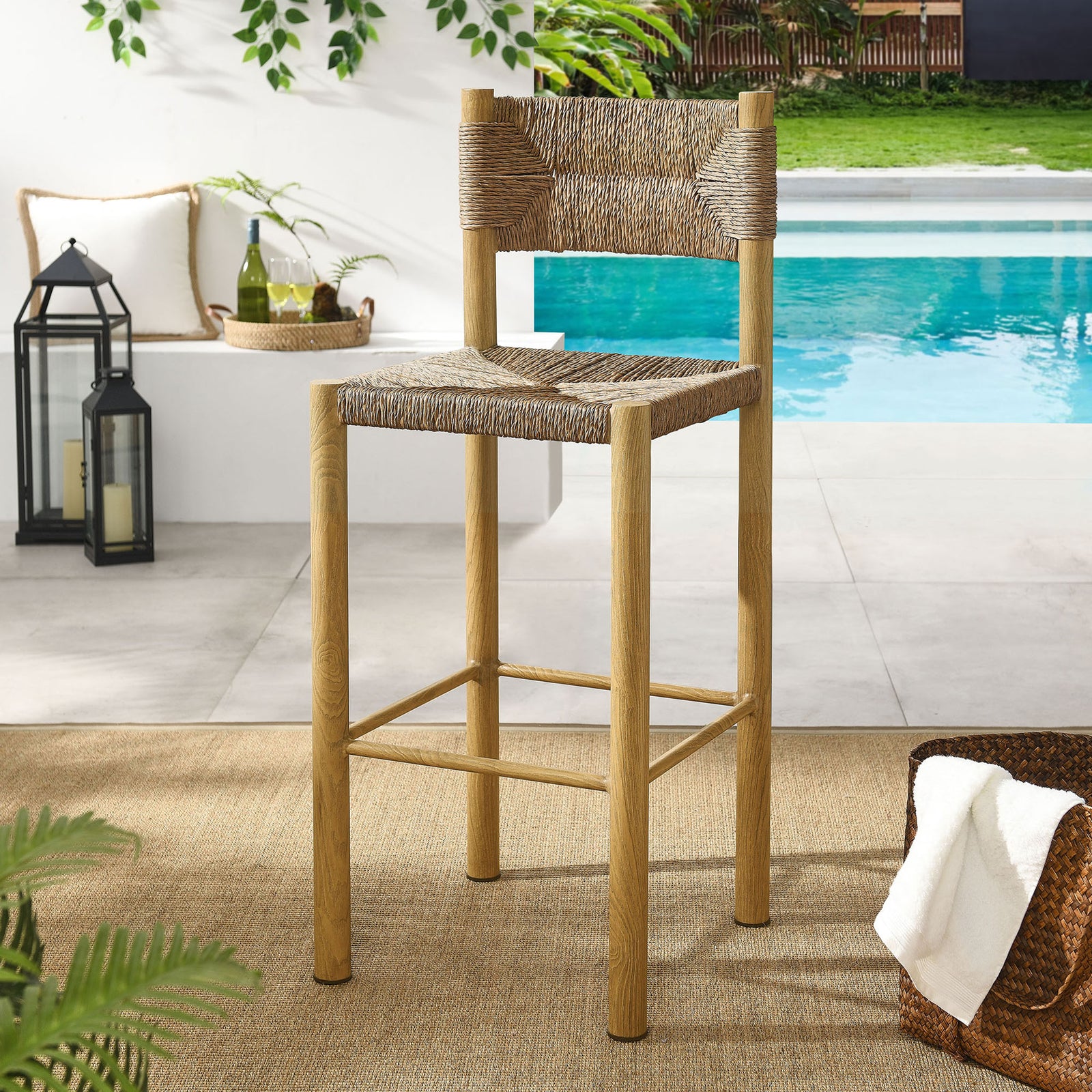 Natural bar stool lends woven warmth beside a modern poolside bar setting || EEI-6984-NAT || front_angle_room