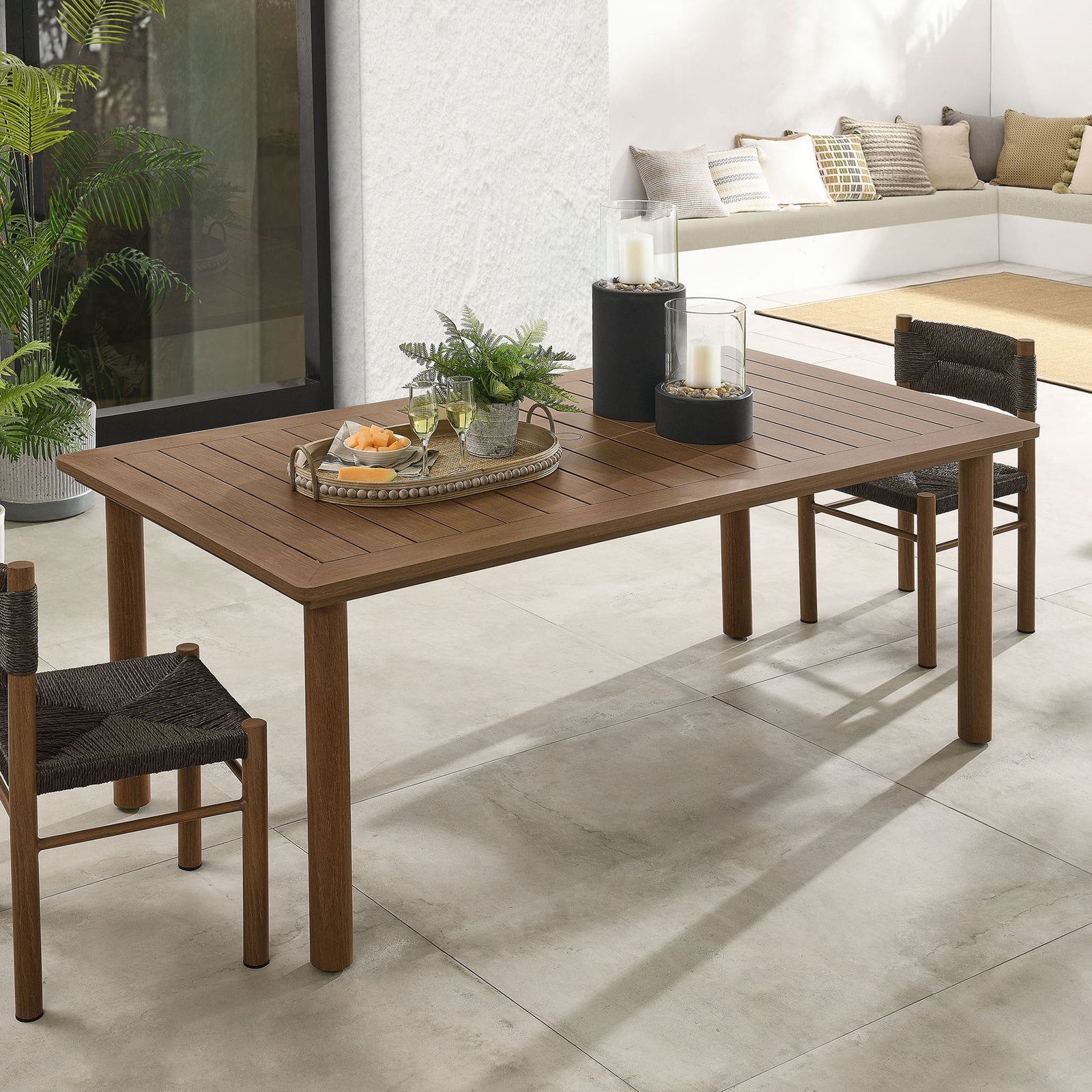 Walnut slatted dining table styled with candles and drinks in a sunlit modern patio setting || EEI-6985-WAL || top_angle_room