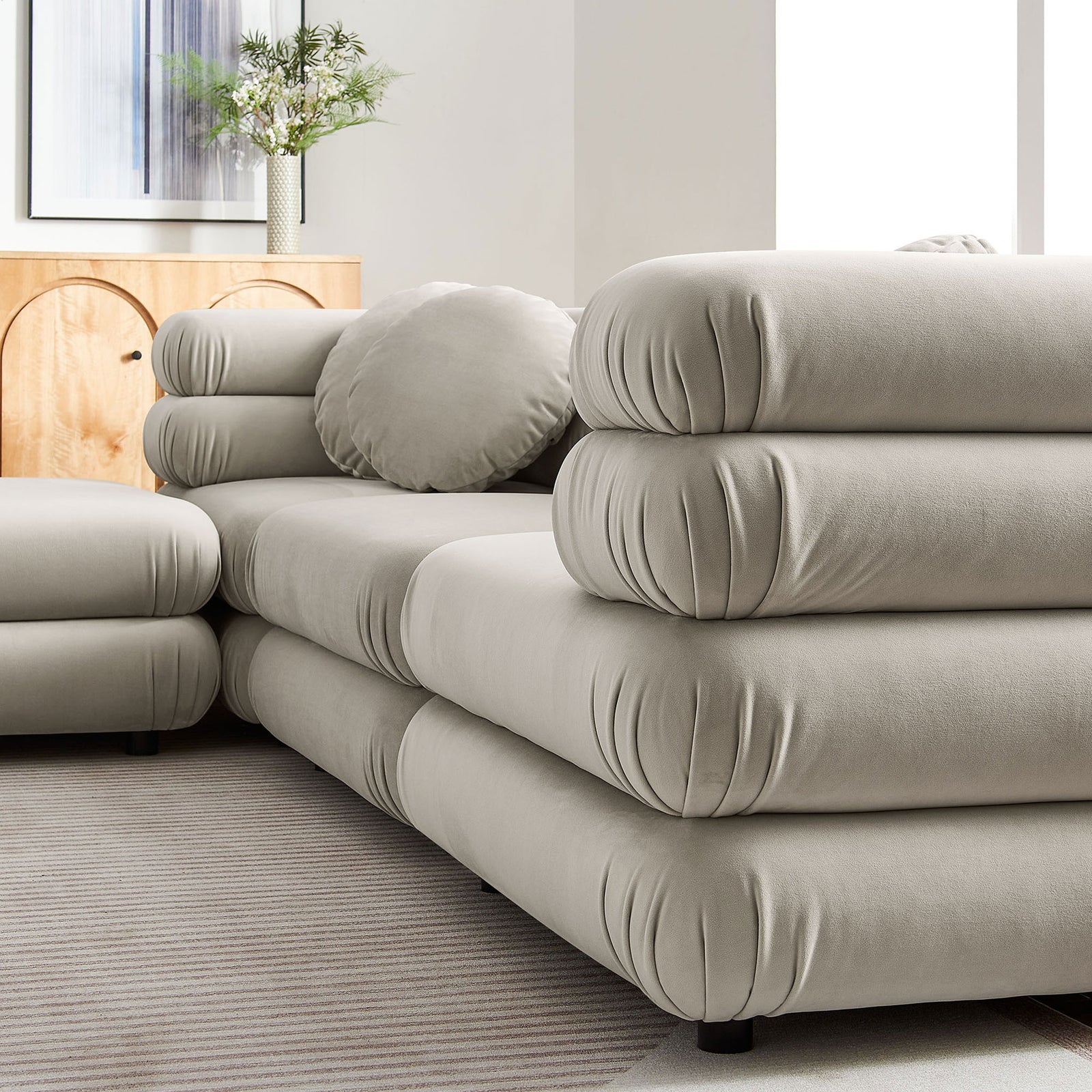 Layered tubular cushions and round pillow on the almond performance velvet sectional in a styled living room || EEI-7004-ALM || detail_room