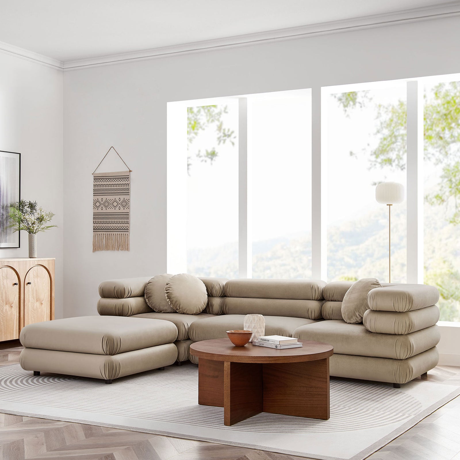Taupe velvet modular sectional and ottoman styled in a bright living room with soft accents || EEI-7004-TAU || front_angle_room