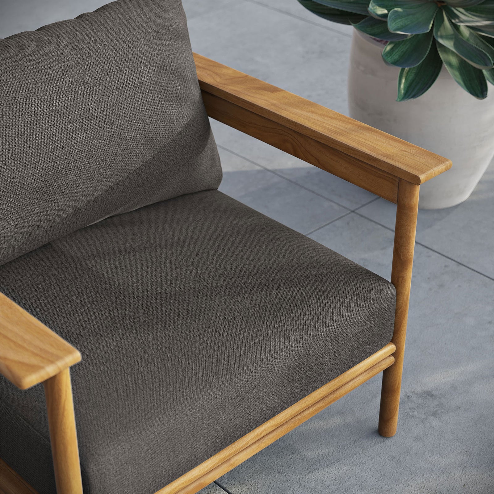 Charcoal cushioned teak armchair arranged on a modern patio beside a large potted succulent || EEI-7007-NAT-FLI || detail_room