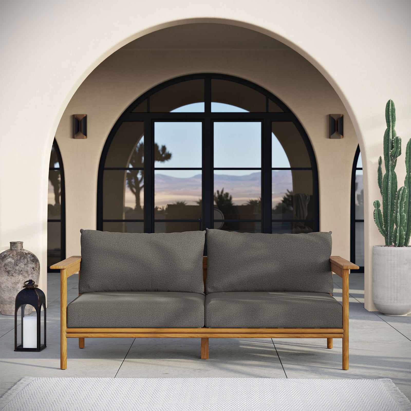 Teak outdoor sofa with charcoal cushions anchoring a modern terrace framed by arched doors. || EEI-7008-NAT-FLI || front_room