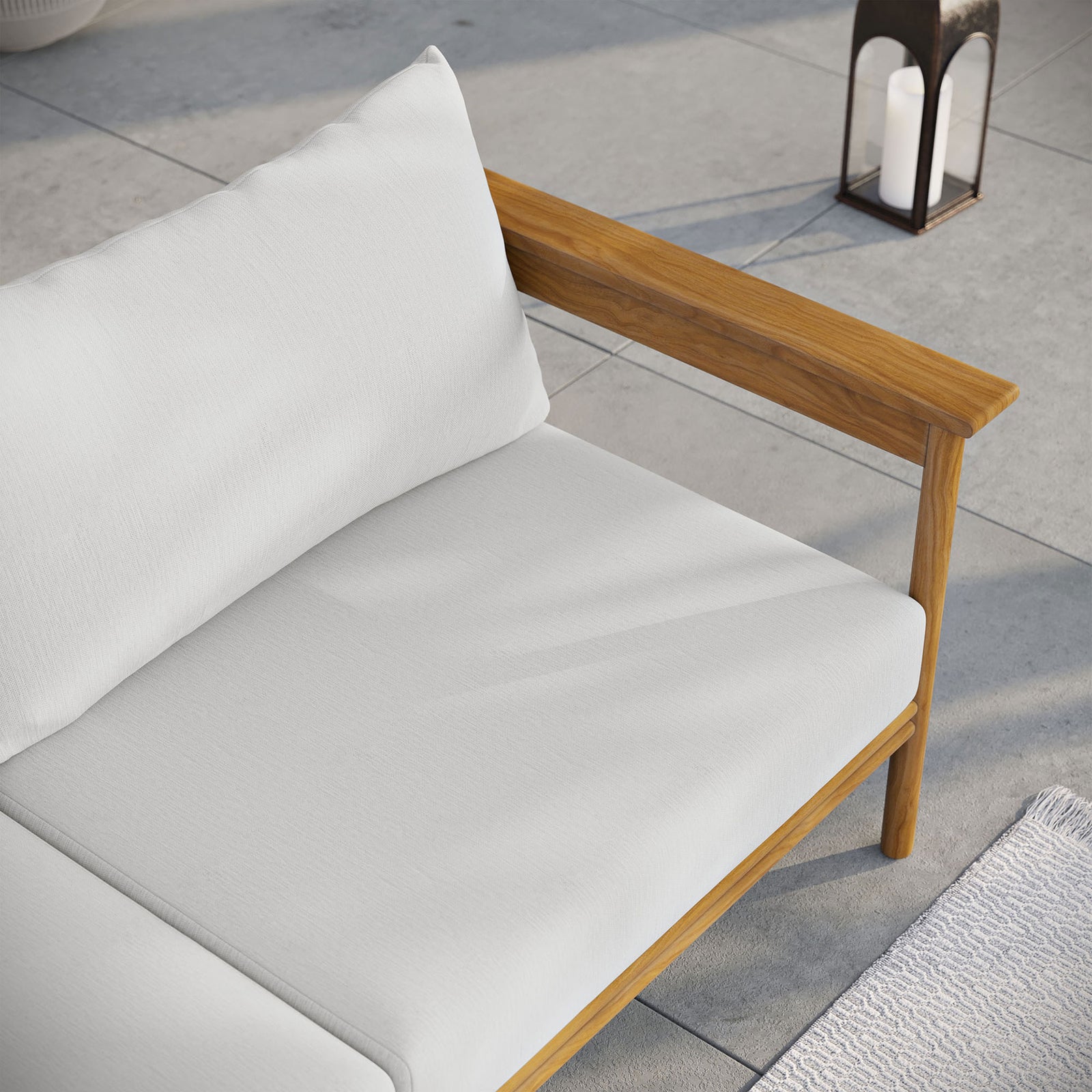 White cushion teak sofa corner styled with lantern lighting and a textured outdoor rug. || EEI-7008-NAT-SAI || detail_room