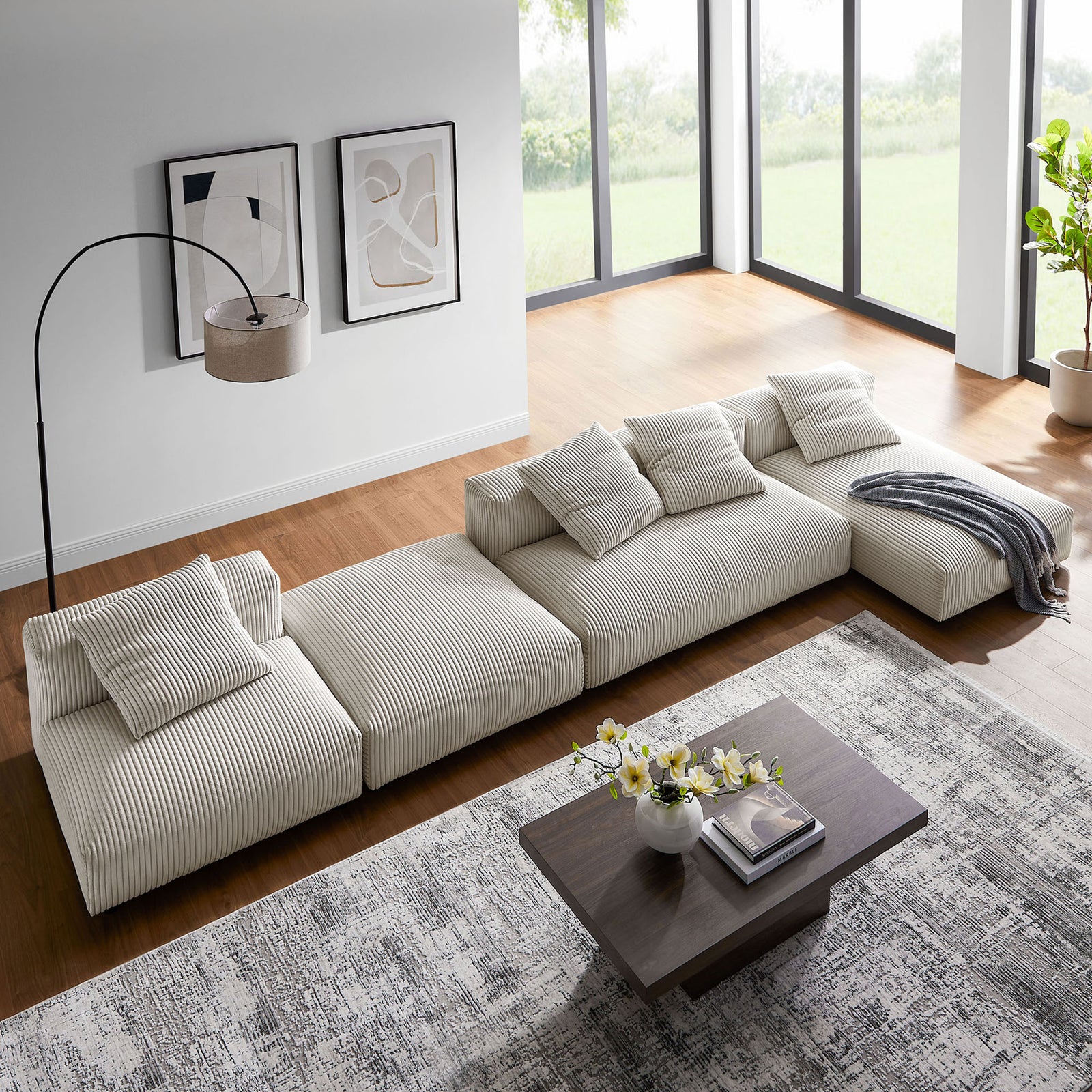 Modular almond corduroy sectional arranged as a long sofa with throw blanket in an airy, windowed room || EEI-7032-ALM || top_angle_partial_room