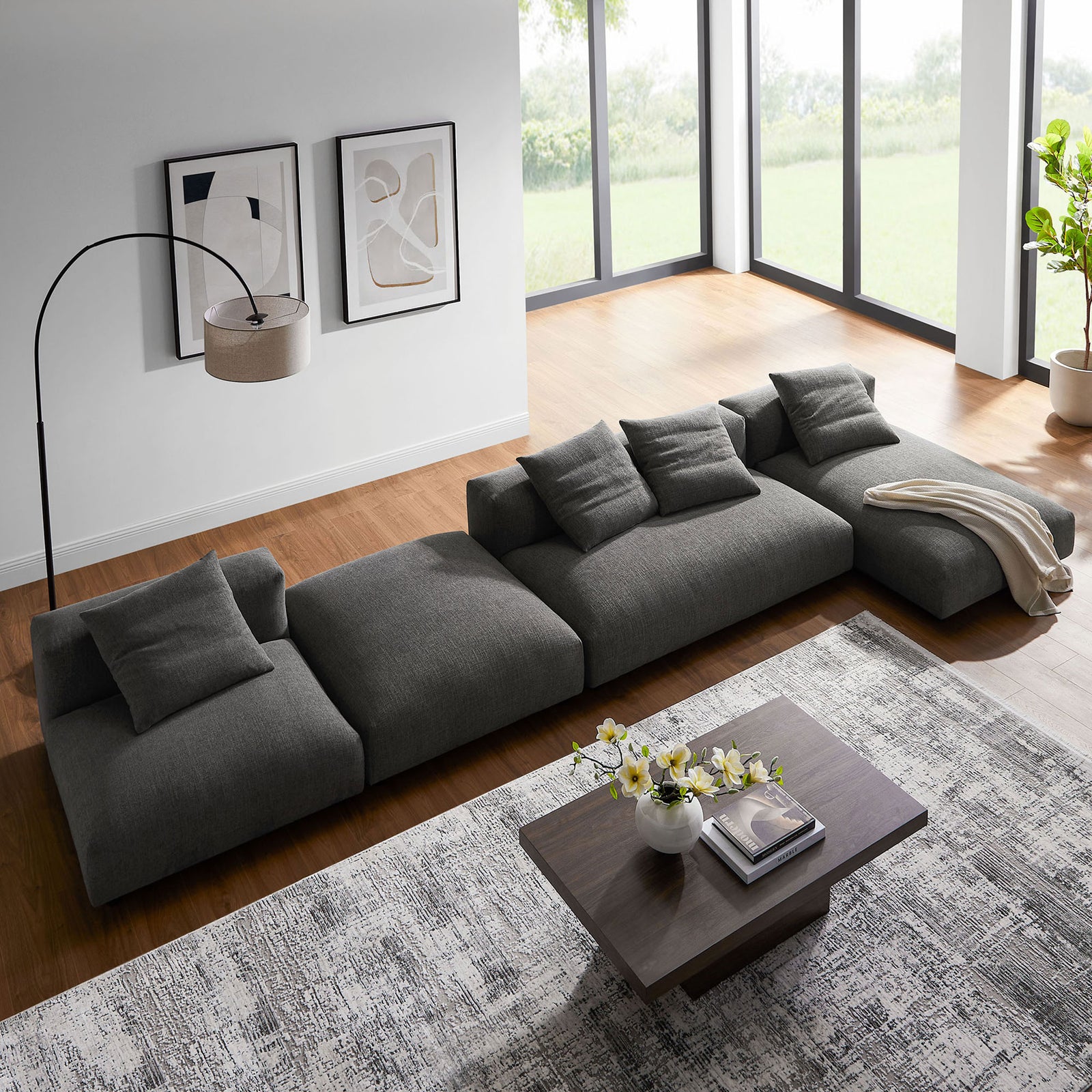Low profile charcoal modular sectional arranged flush to the floor beside a wood coffee table and decor || EEI-7033-CHA || top_angle_room