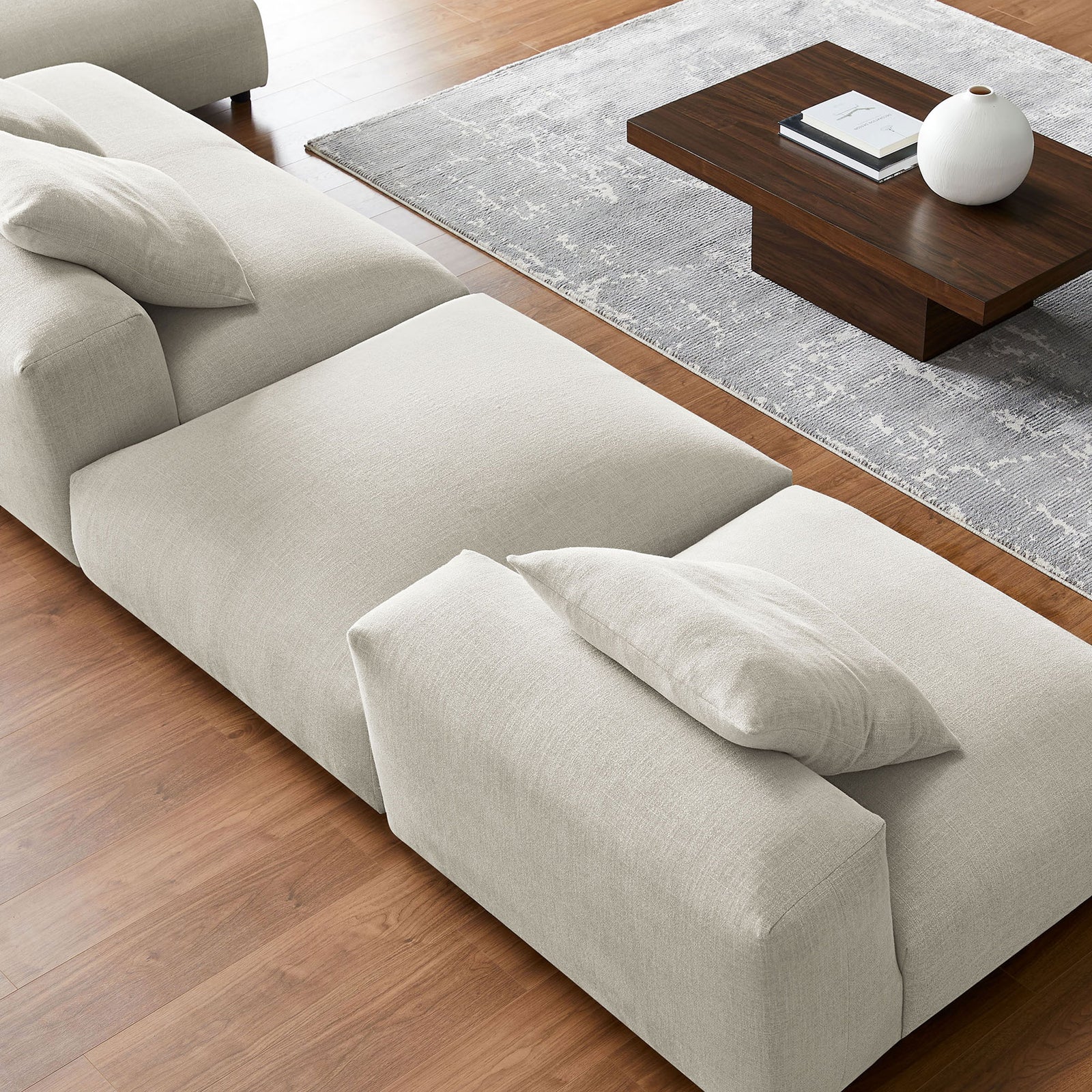 Linen modular sectional detail highlighting smooth upholstery beside a modern wood coffee table || EEI-7033-LIN || detail_room