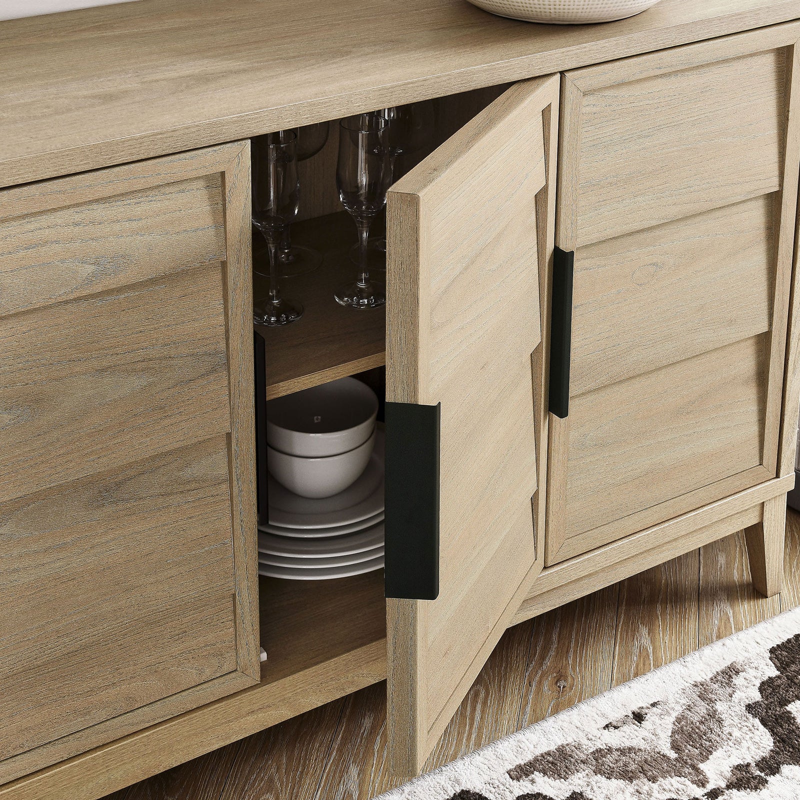 Sinya sideboard doors partially open to show organized glassware and dinnerware on the interior shelves. || EEI-7040-LOA || storage_open_room