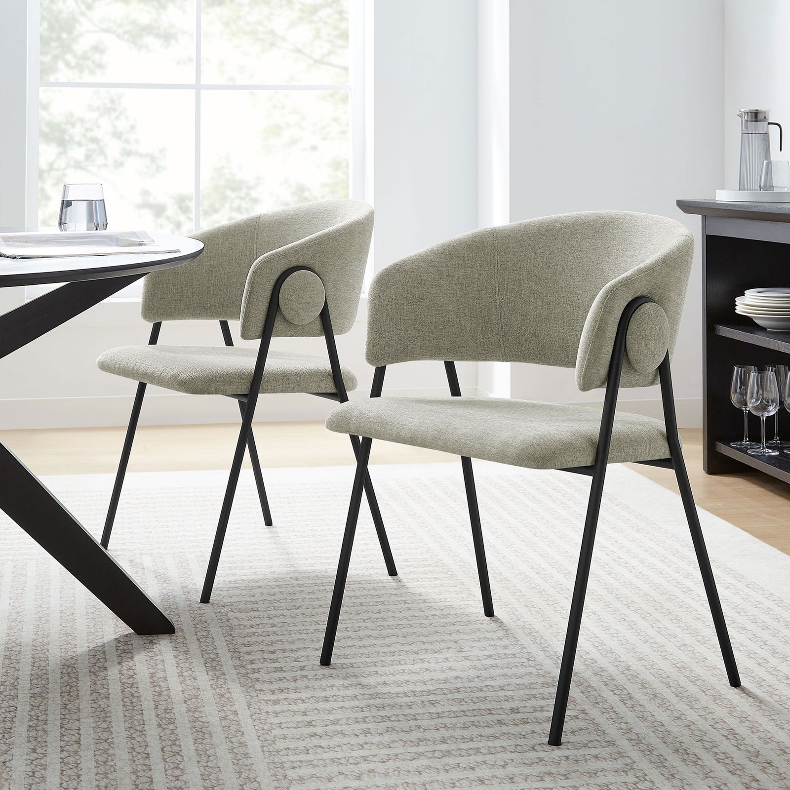 Pair of taupe chenille dining chairs around a modern table in a light filled dining space. || EEI-7045-TAU-BLK || front_angle_multi_room