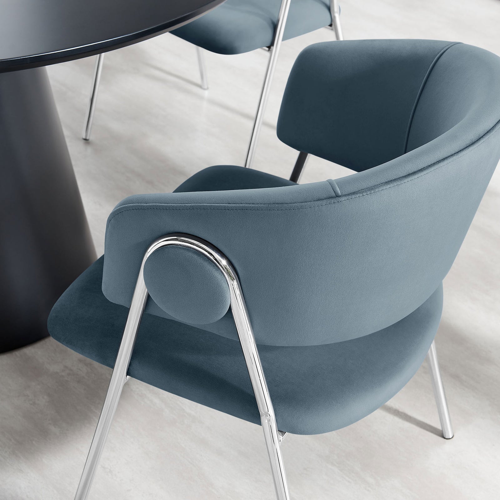 Cadet blue velvet dining chair tucked at a modern table, adding soft texture and curved comfort. || EEI-7046-CAD-SLV || front_angle_room
