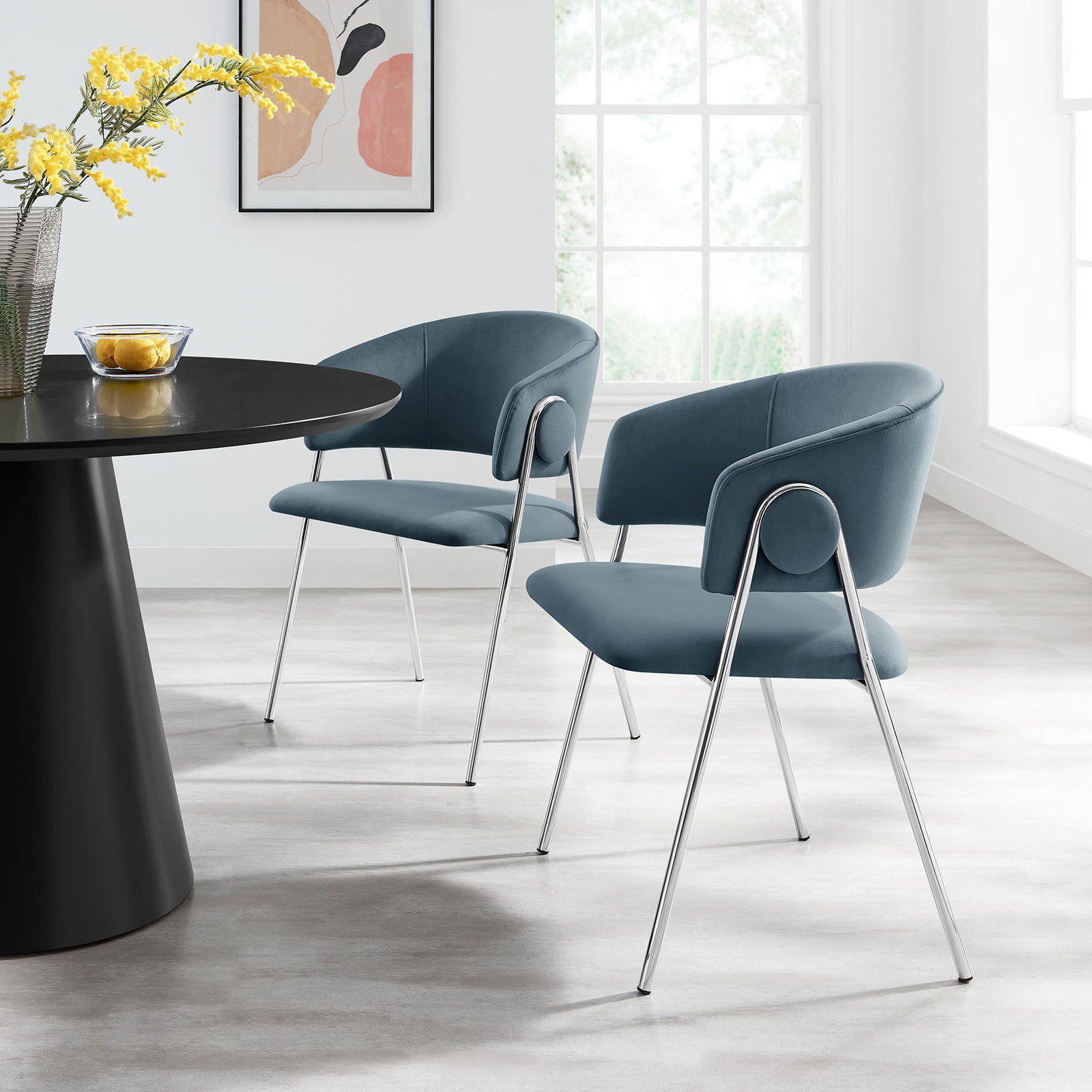 Two cadet blue velvet dining chairs styled around a contemporary table in a bright dining room. || EEI-7046-CAD-SLV || front_angle_multi_room