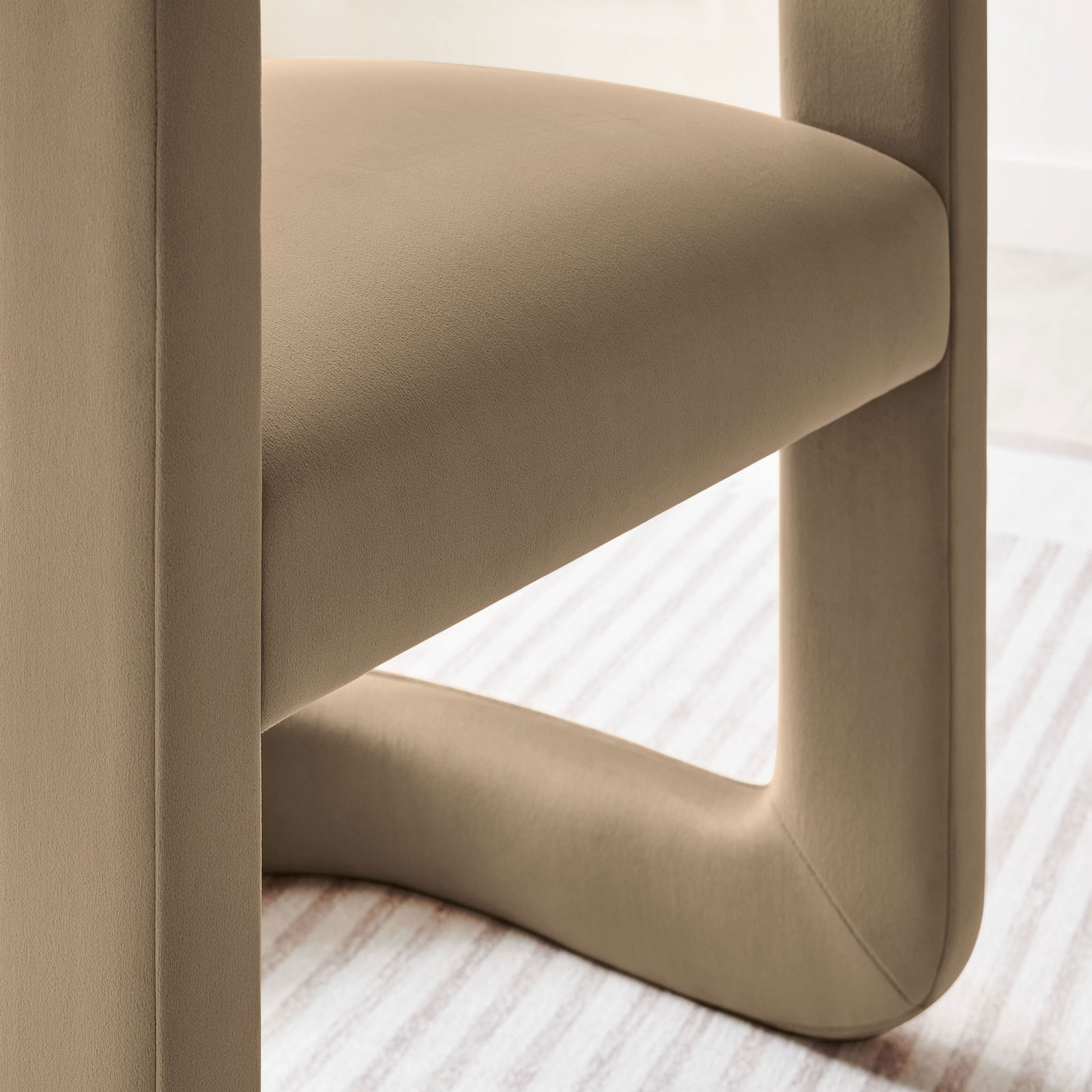 Detail of taupe velvet dining chair seat and base styled over a striped area rug. || EEI-7052-TAU || detail_room