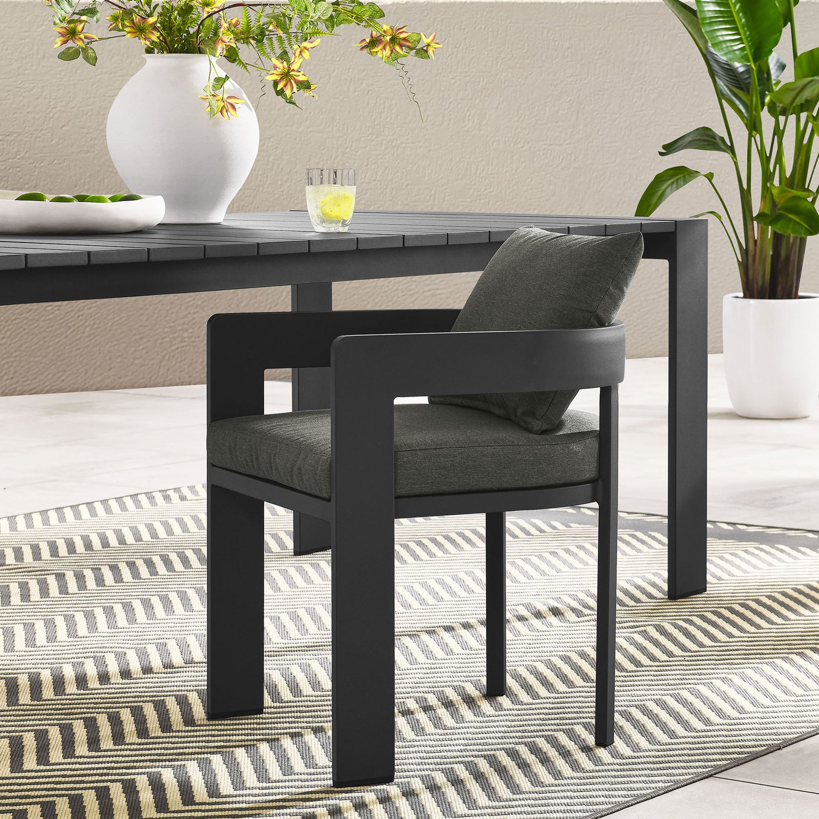 Charcoal Tahoe patio dining chair with dark gray cushions styled at a modern outdoor dining table || EEI-7053-GRY-CHA || front_angle_room