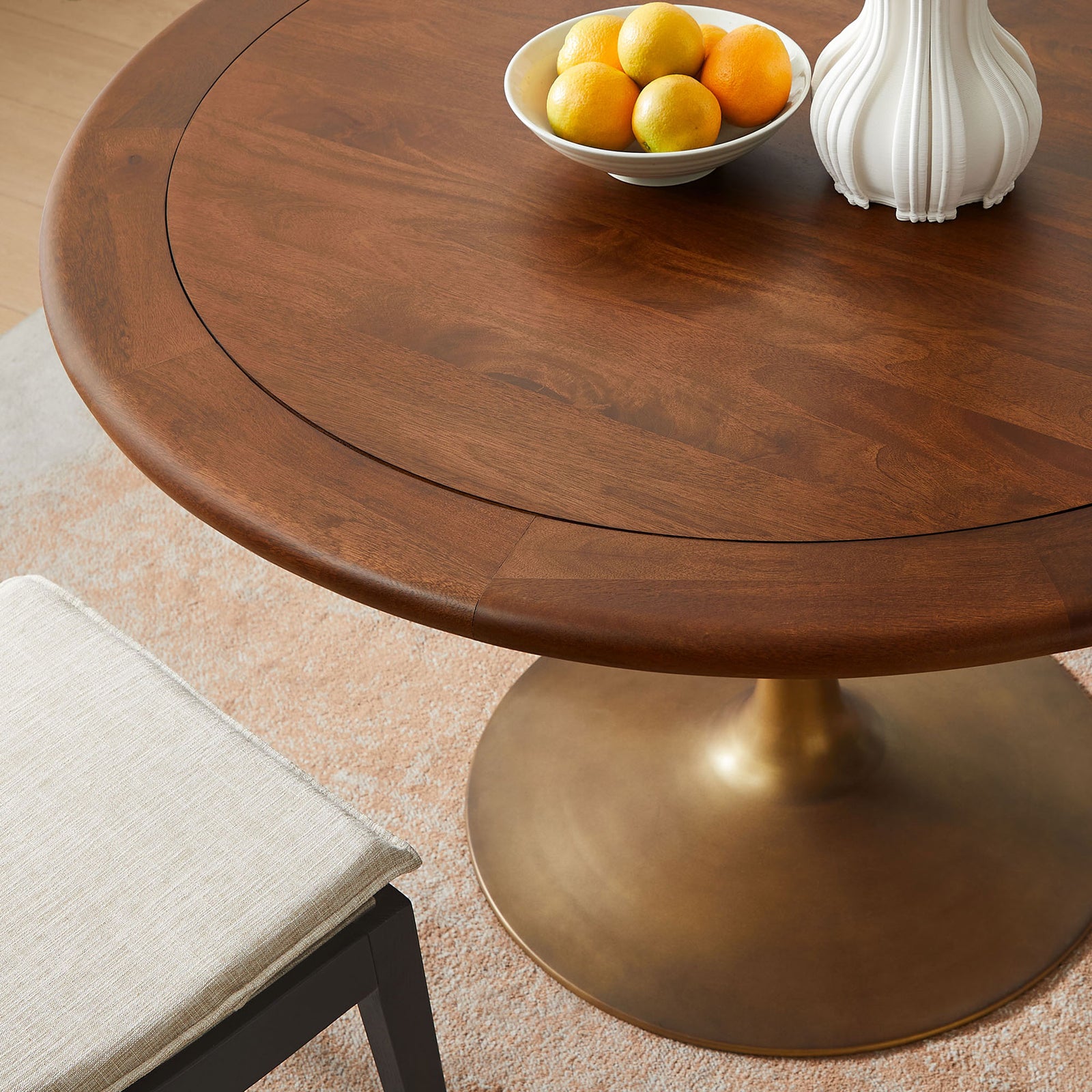 Walnut dining tabletop styled with fruit and decor, highlighting the warm wood tone and brass pedestal base || EEI-7070-BRA-WAL || detail_room