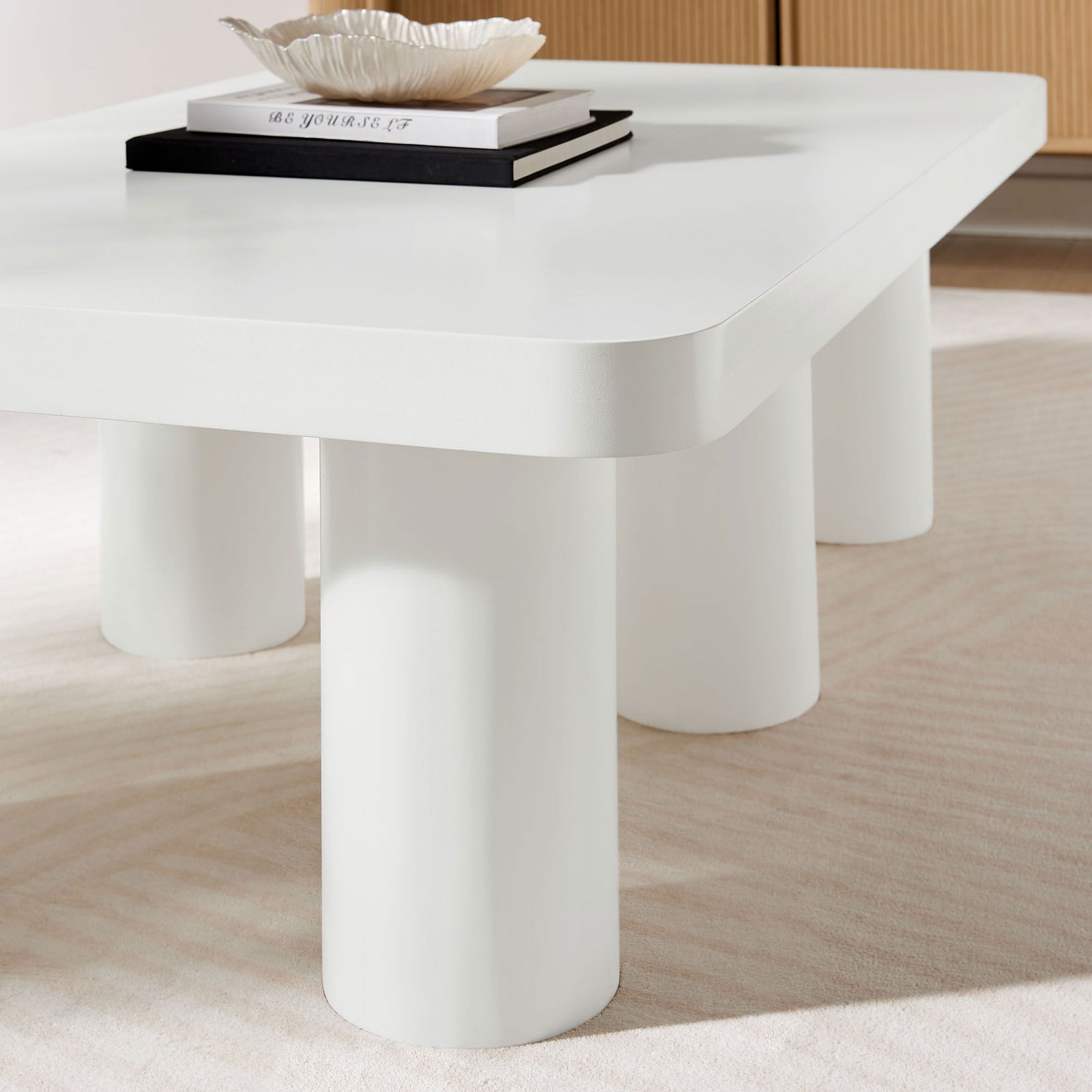 Rounded white tabletop and sturdy cylinder legs styled on a soft neutral rug || EEI-7072-WHI || leg_room