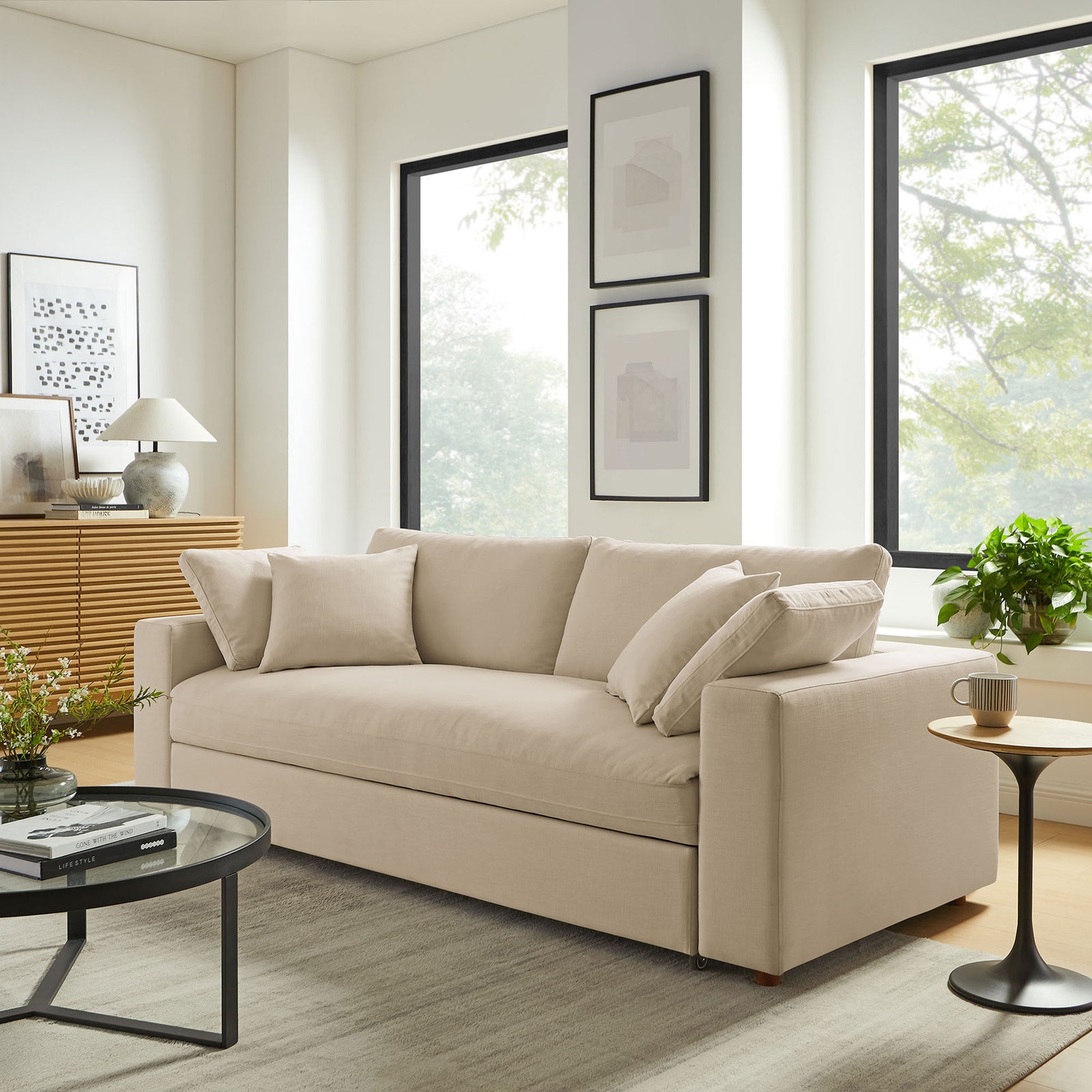 Light beige sleeper sofa anchoring a bright contemporary living room with large windows and layered textures || EEI-7080-LBG || front_angle_room