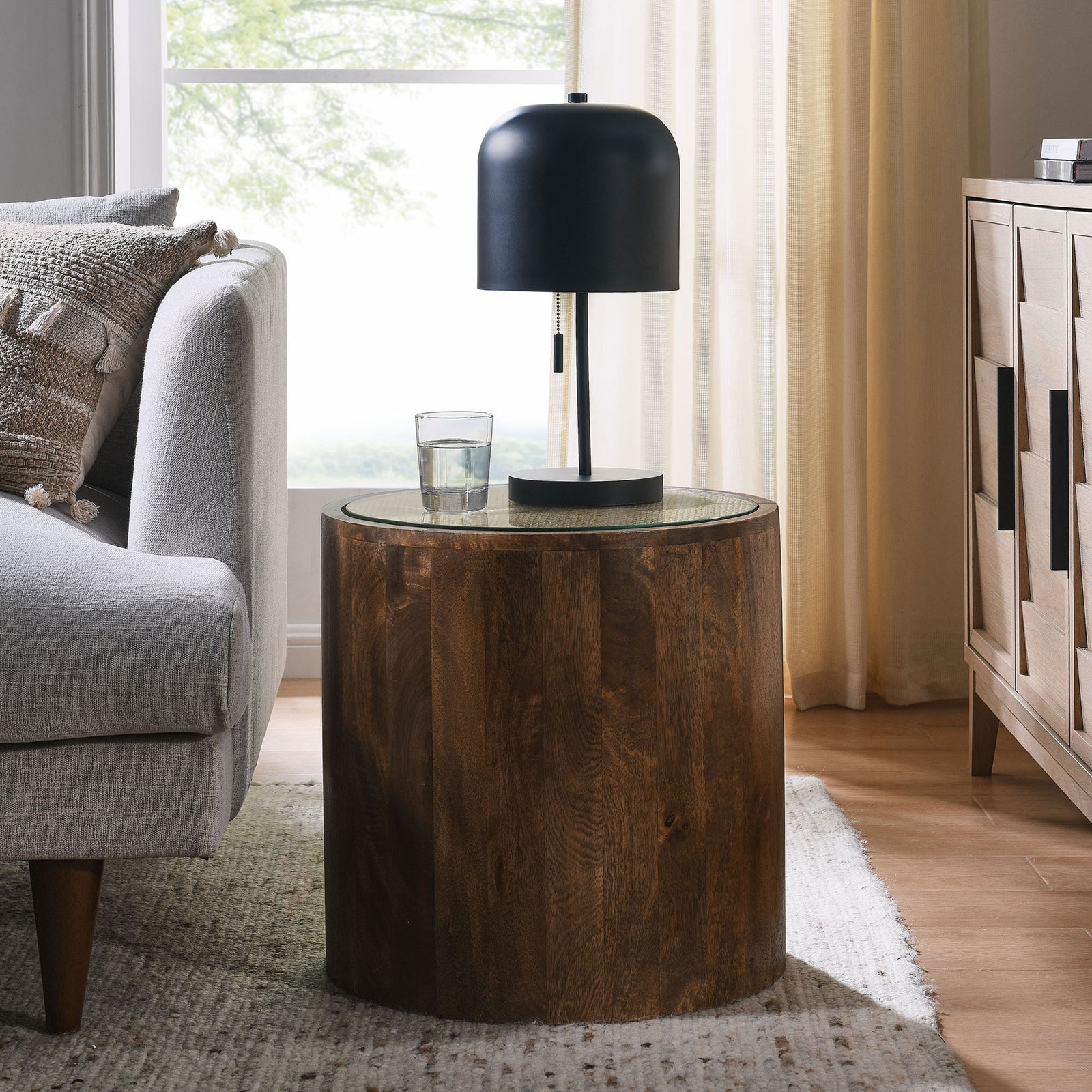 Walnut drum side table bringing warm natural texture next to a sofa in a bright living room || EEI-7085-WAL || front_angle_room