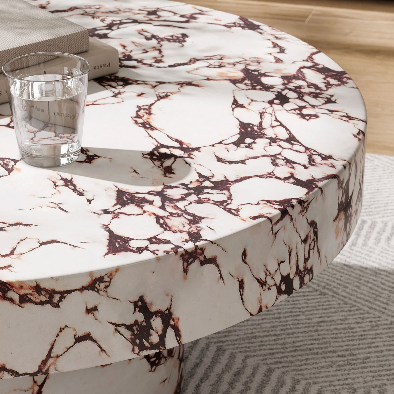 Red marble look coffee table styled indoors with glass and book on a textured area rug || EEI-7091-RED || detail_room