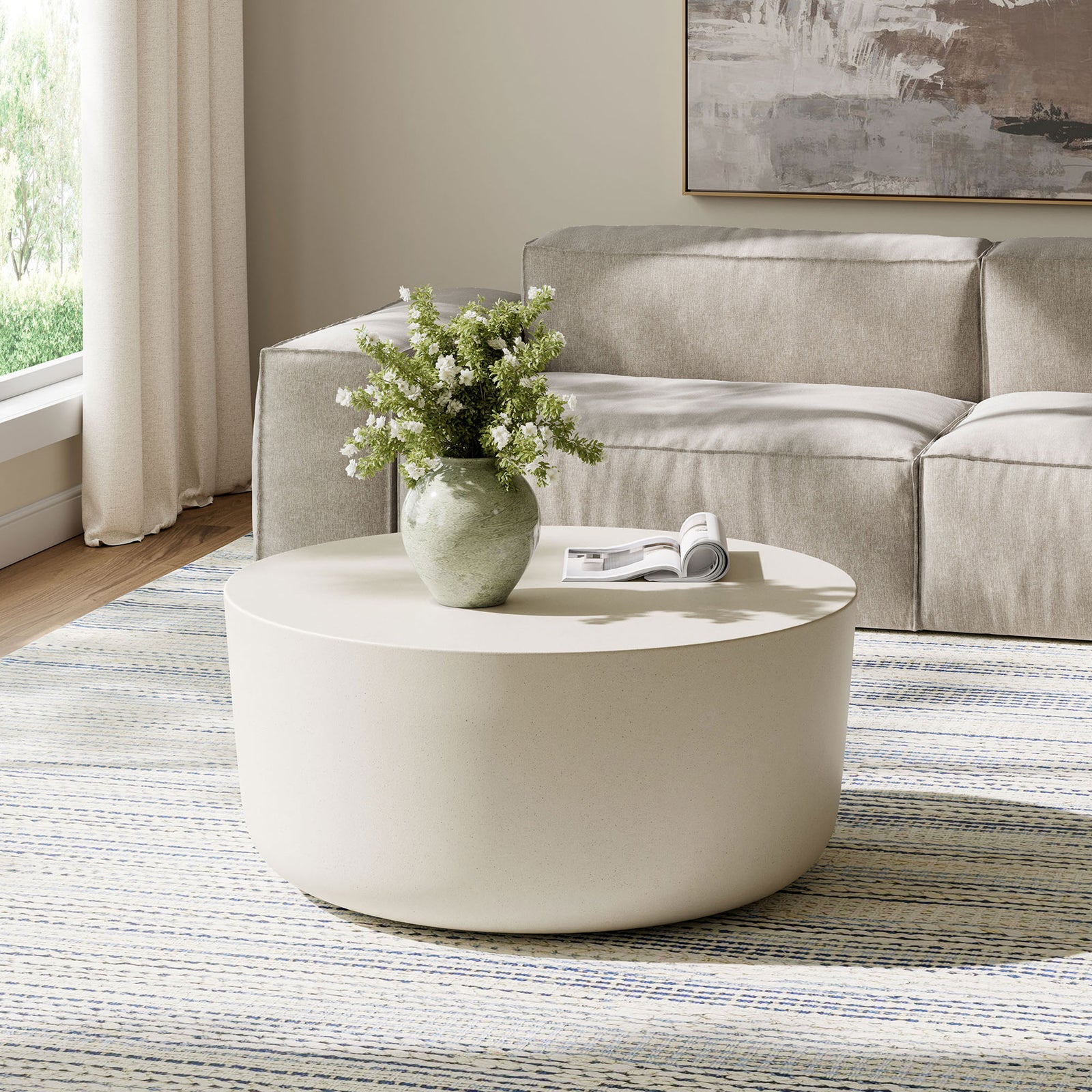 White concrete drum coffee table anchoring a contemporary living room with airy, minimalist style || EEI-7099-WHI || front_angle_room