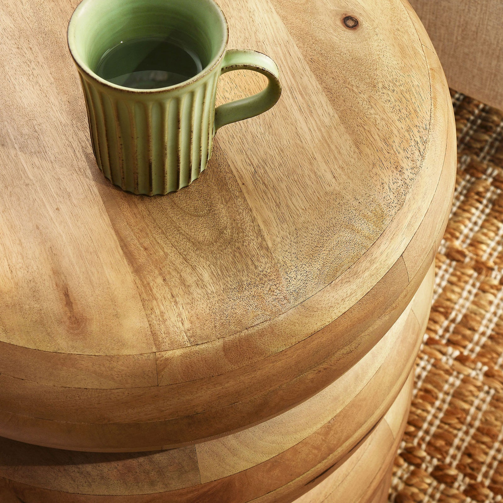 Tabletop detail with warm mango wood grain, styled with a mug on a textured rug || EEI-7106-NAT || detail_room