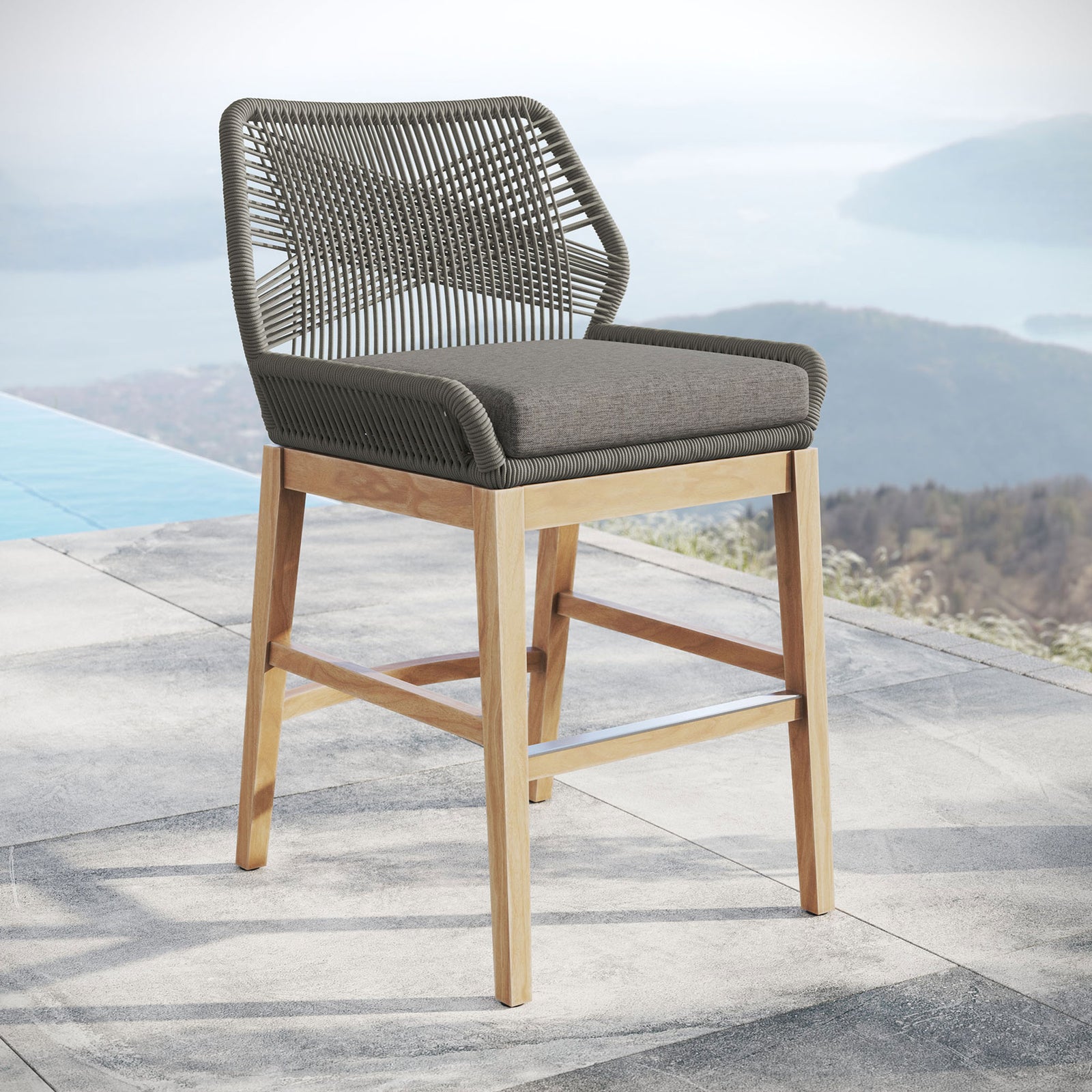 Gray graphite rope counter stool with gray cushion and teak legs styled by an infinity pool and mountain view. || EEI-7126-GRY-GPH || front_angle_room