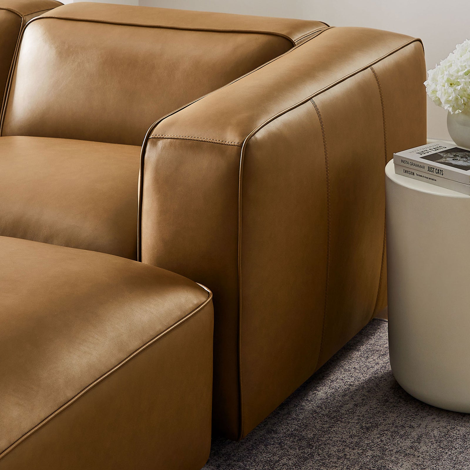 Chunky arm and tailored stitching of the camel vegan leather modular sofa styled next to a modern side table || EEI-7131-CAM || detail_room