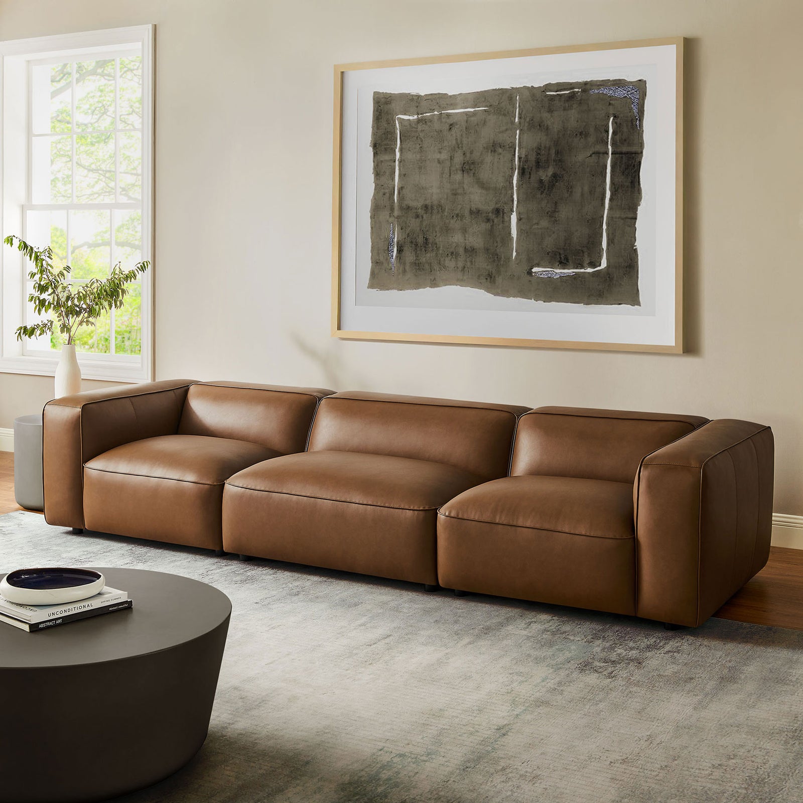 Coffee vegan leather modular sofa styled in a sunlit living room with rug, art, and round table || EEI-7132-COF || front_room