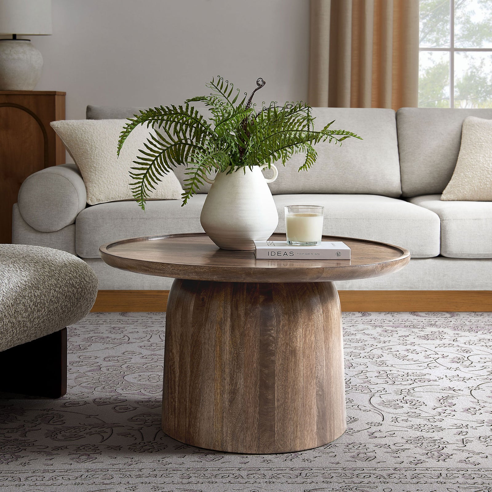 Round mango wood coffee table anchors the living room with a warm walnut tone and modern drum silhouette || EEI-7144-WAL || front_angle_room