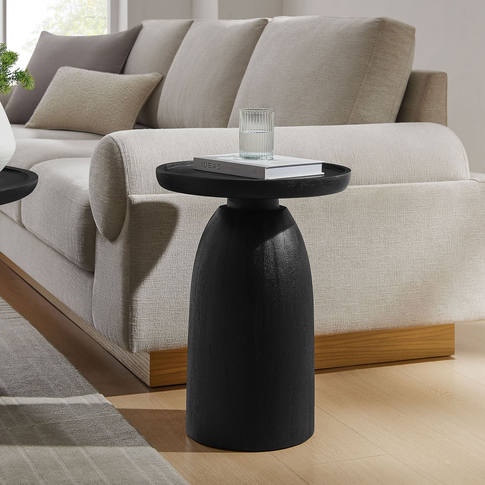 Sculptural black mango wood side table bringing bold contrast and modern warmth to the living room. || EEI-7145-BLK || front_angle_room